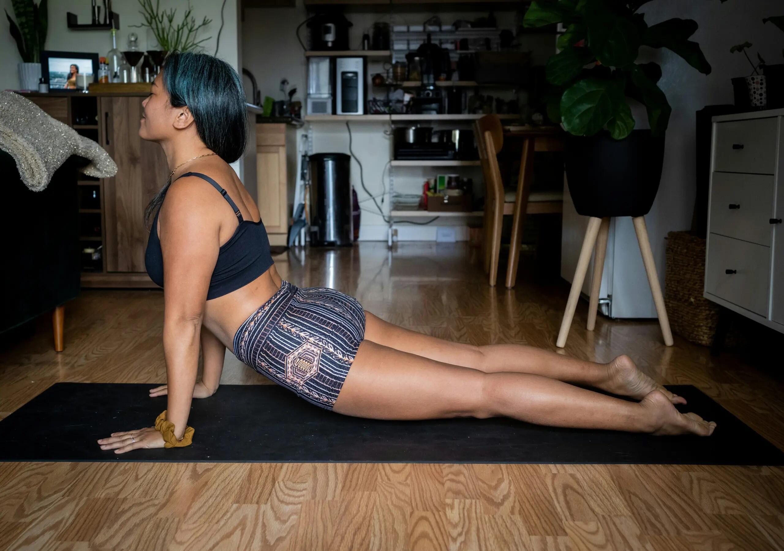 Ragazza esegue una posizione di yoga in casa.