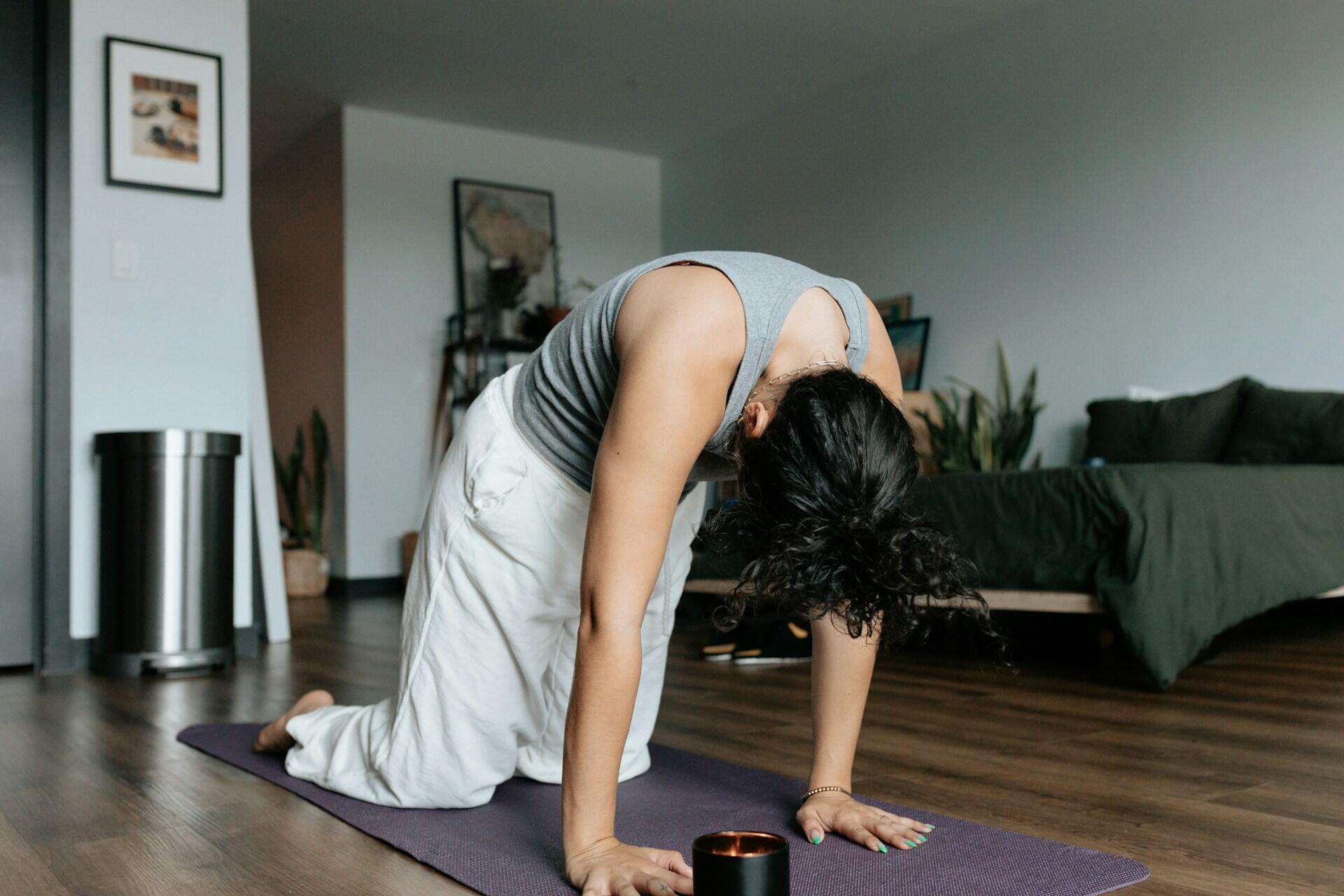 Una ragazza esegue stretching per la schiena in casa.