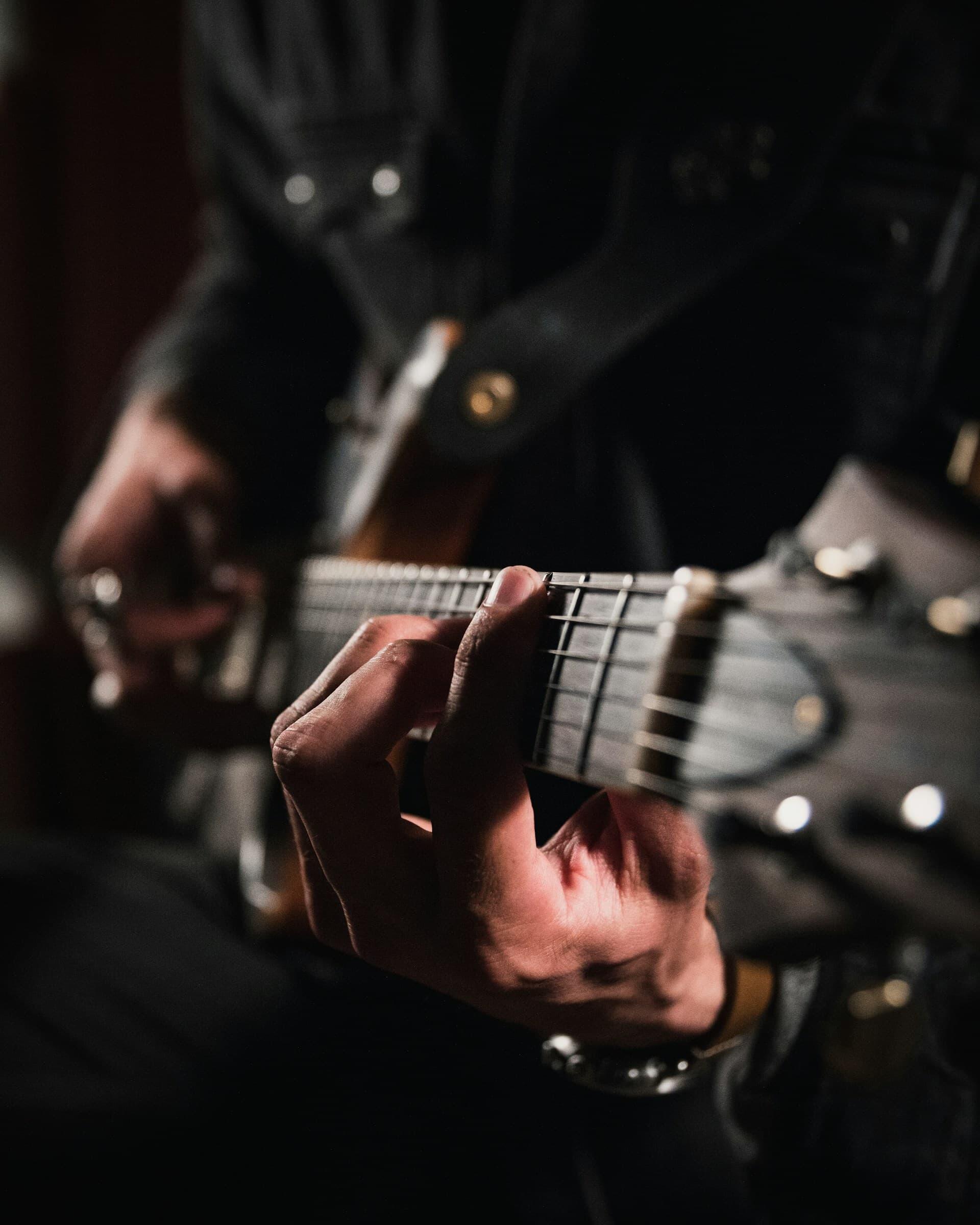 エレキギターの弦を押さえるギタリストの手元