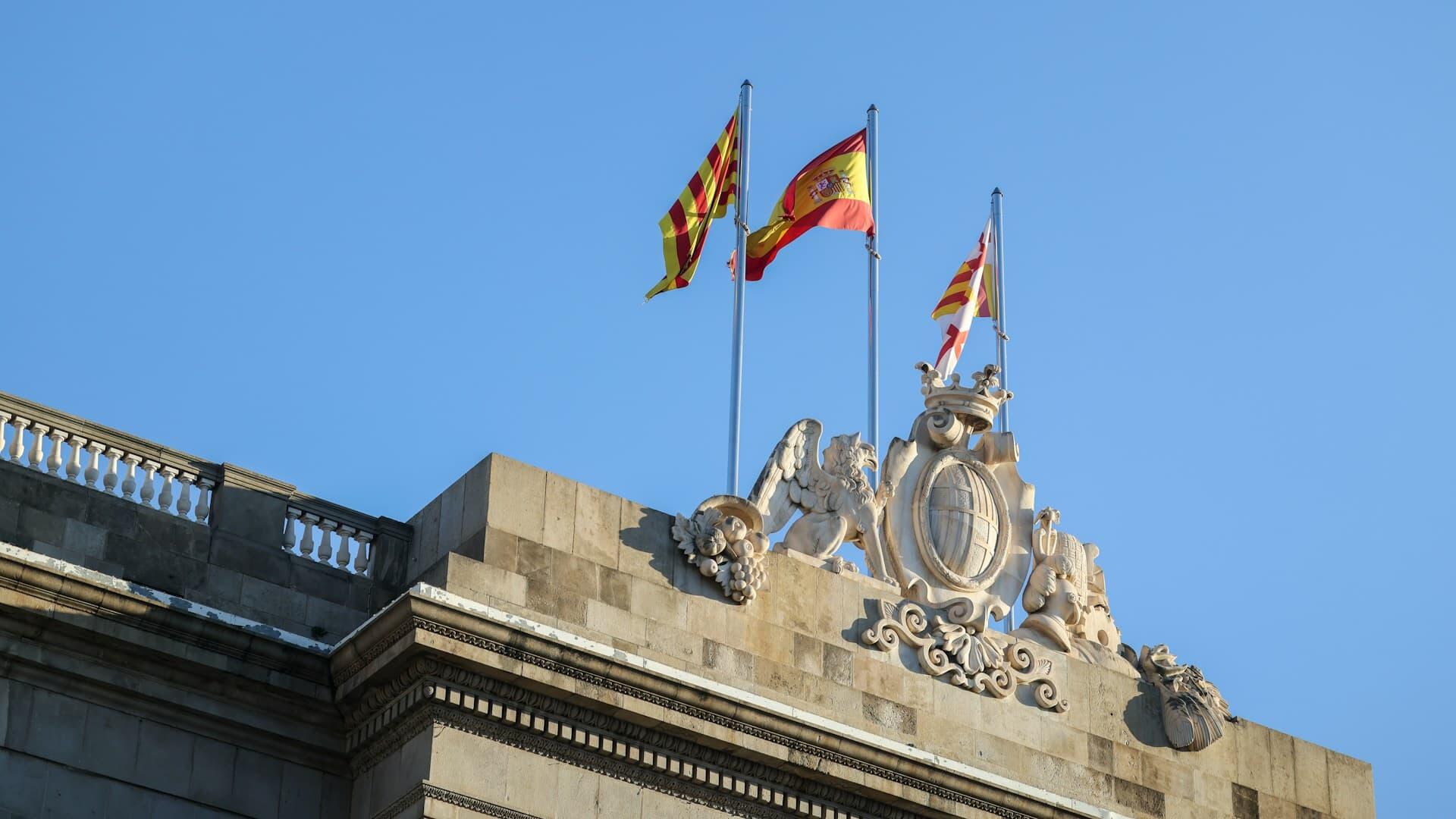 バルセロナの歴史的建造物に掲げられたスペイン国旗とカタルーニャ旗
