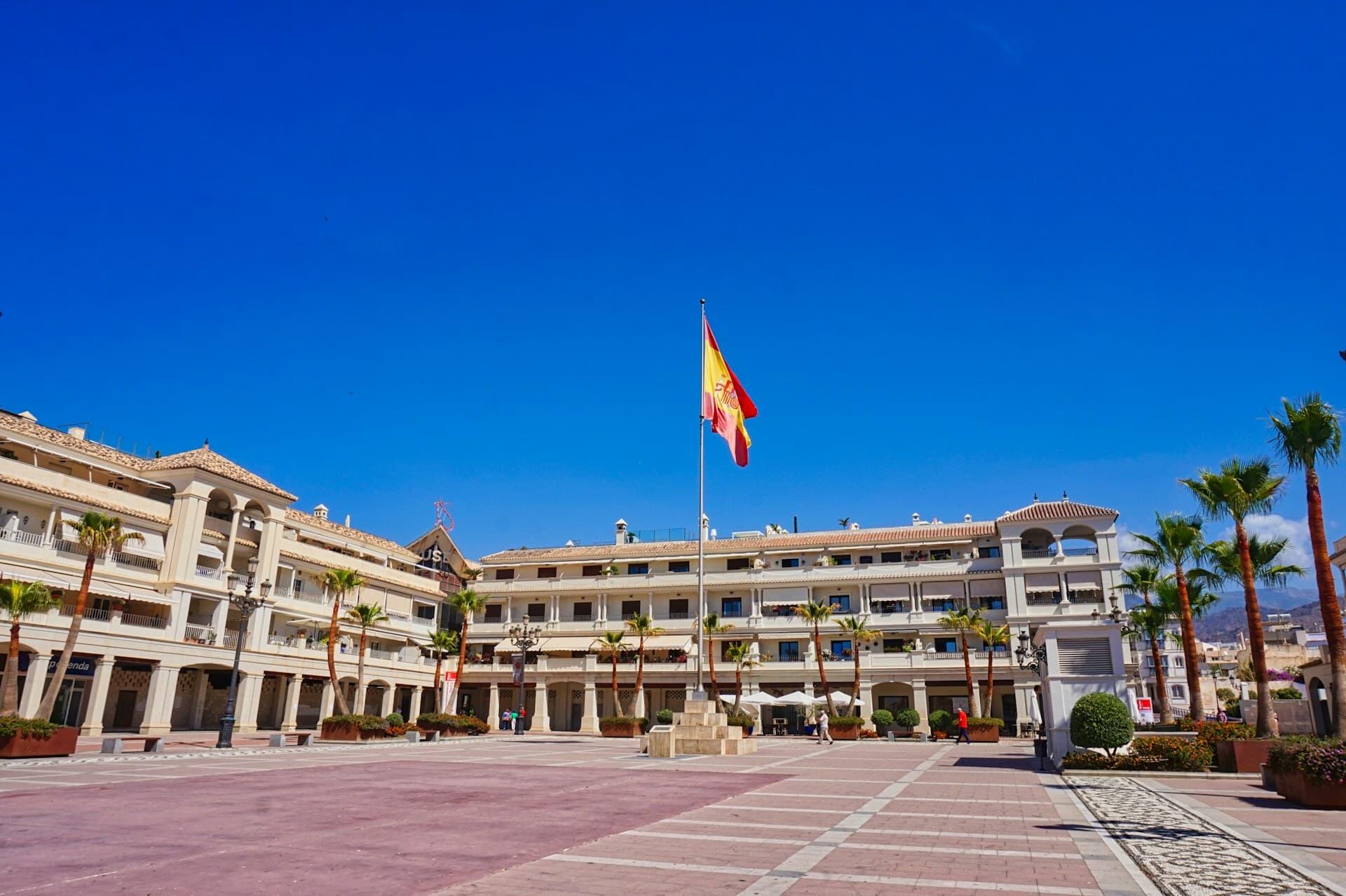 スペイン国旗がはためくスペインの広場と街並み