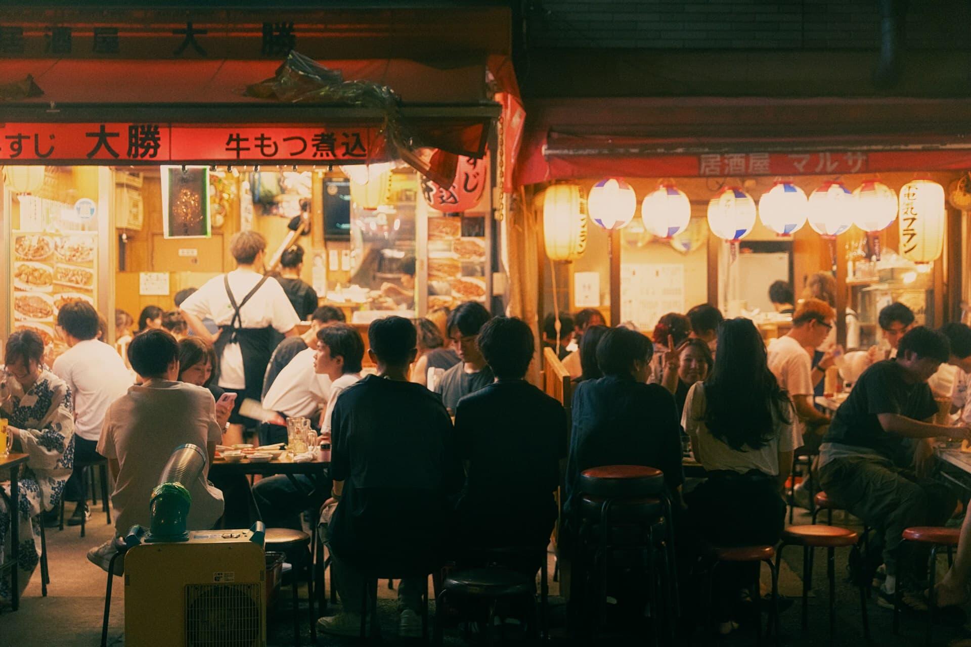 赤提灯が灯る日本の居酒屋で食事を楽しむ人々