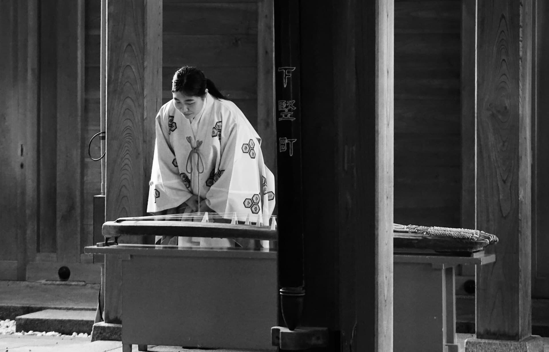 伝統的な装束で琴を演奏する日本の民謡や邦楽の奏者