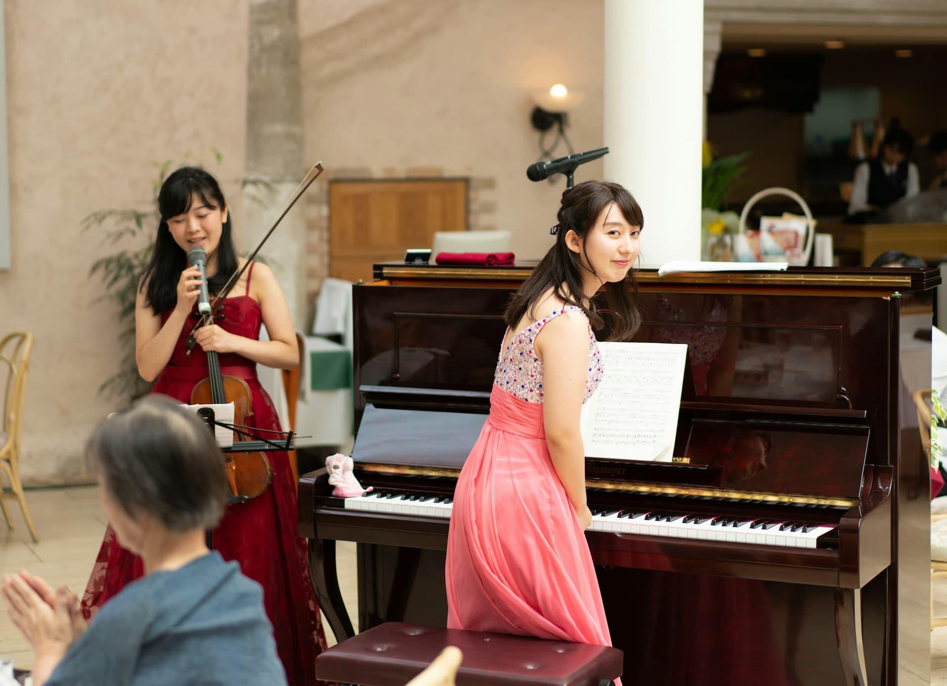 ピアノとバイオリンで演奏する日本人女性の音楽パフォーマンス