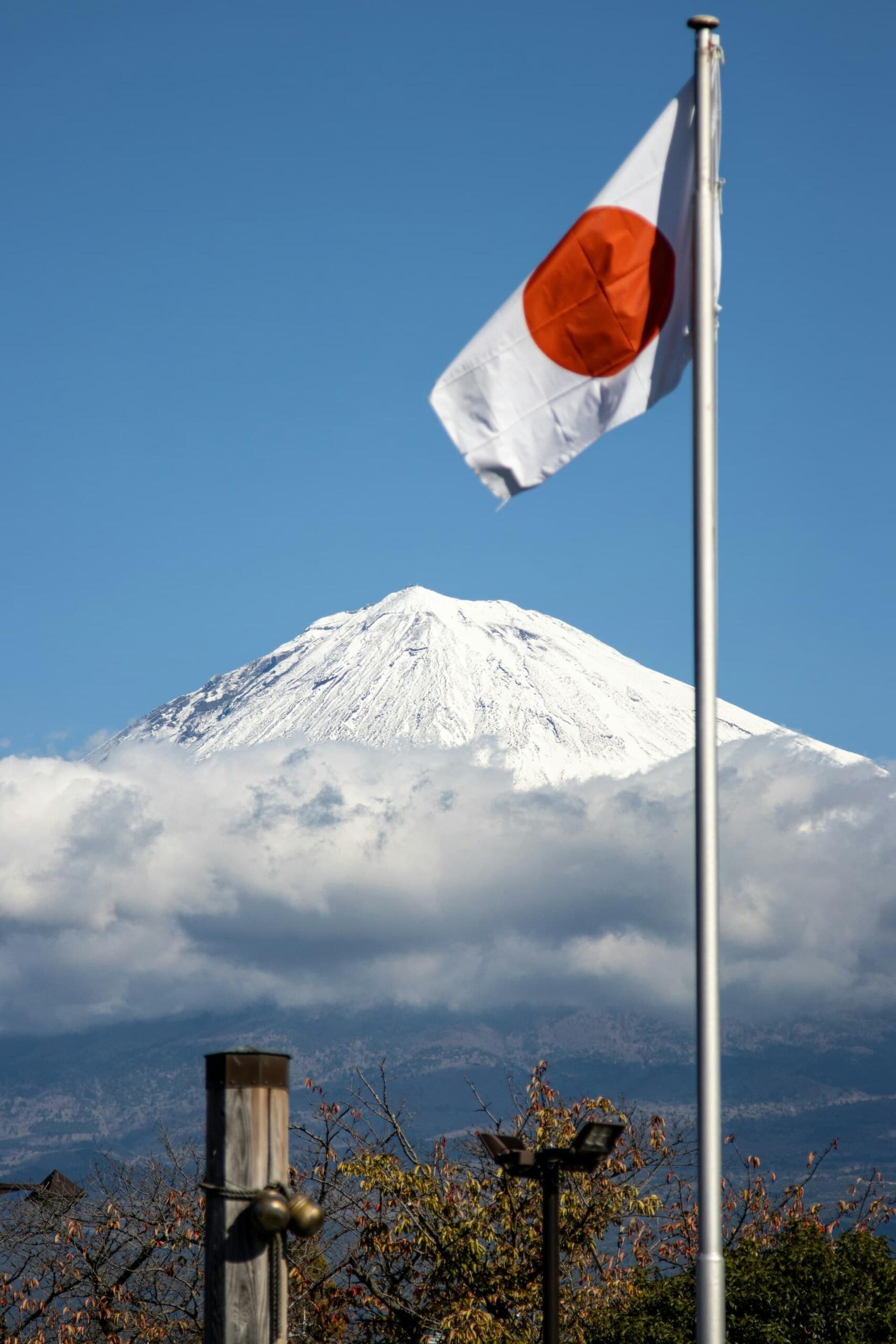雪をかぶった山を背に翻る日章旗