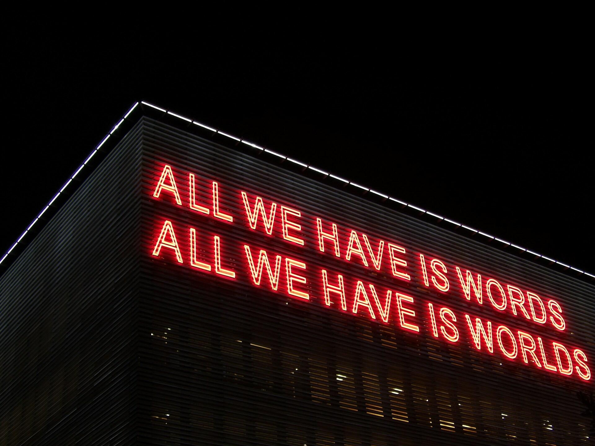 Šviečiantis raudonas užrašas ant sienos "all we have is words"
