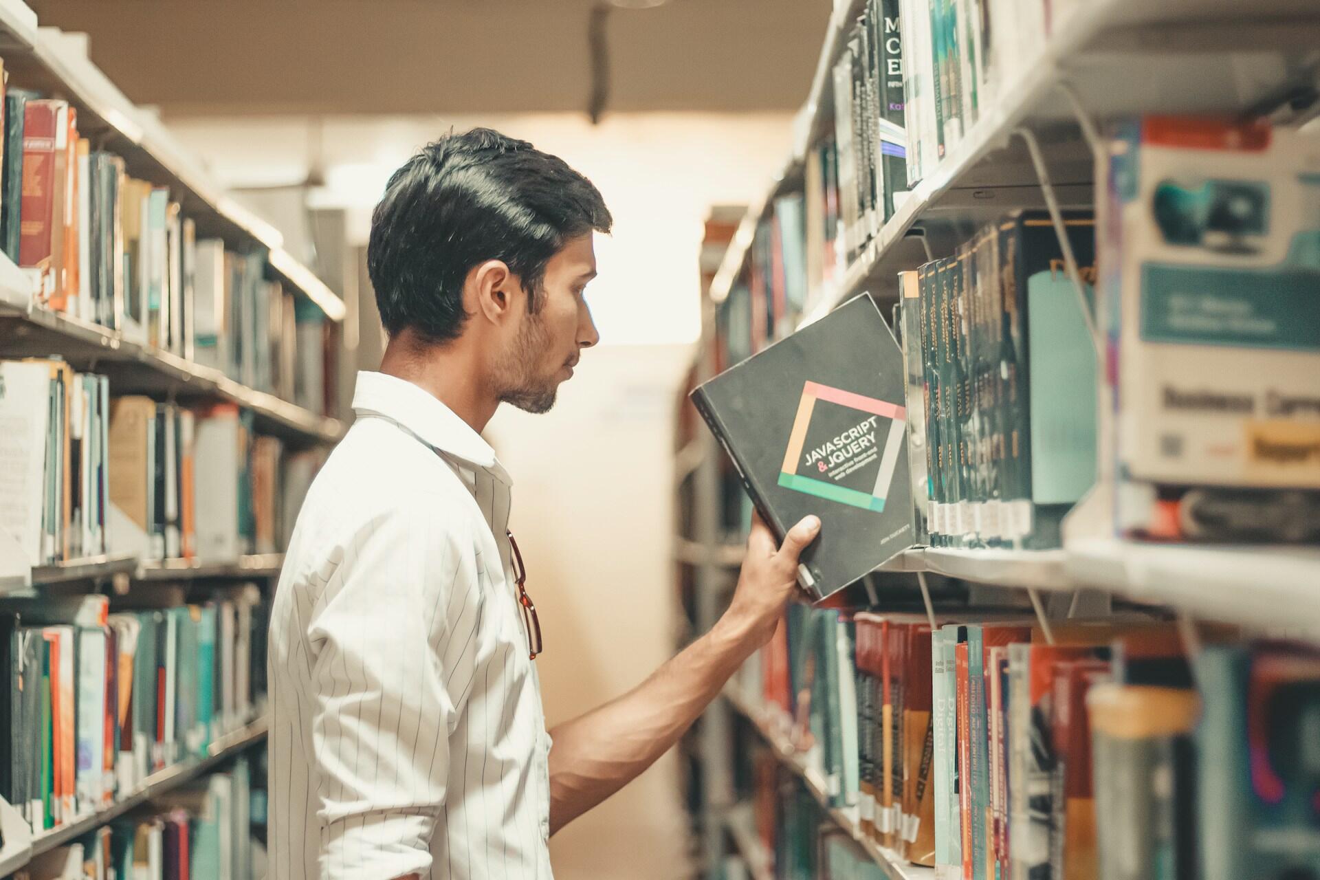 Studentas bibliotekoje su knyga