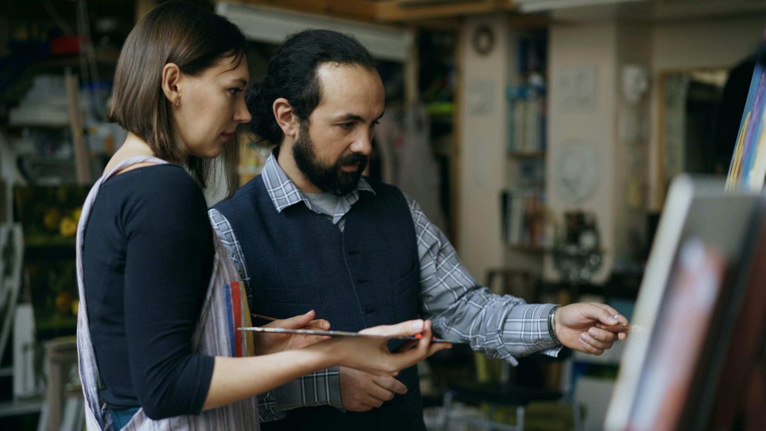 Dailės mokytojas aiškina spalvų derinimą mokinei.