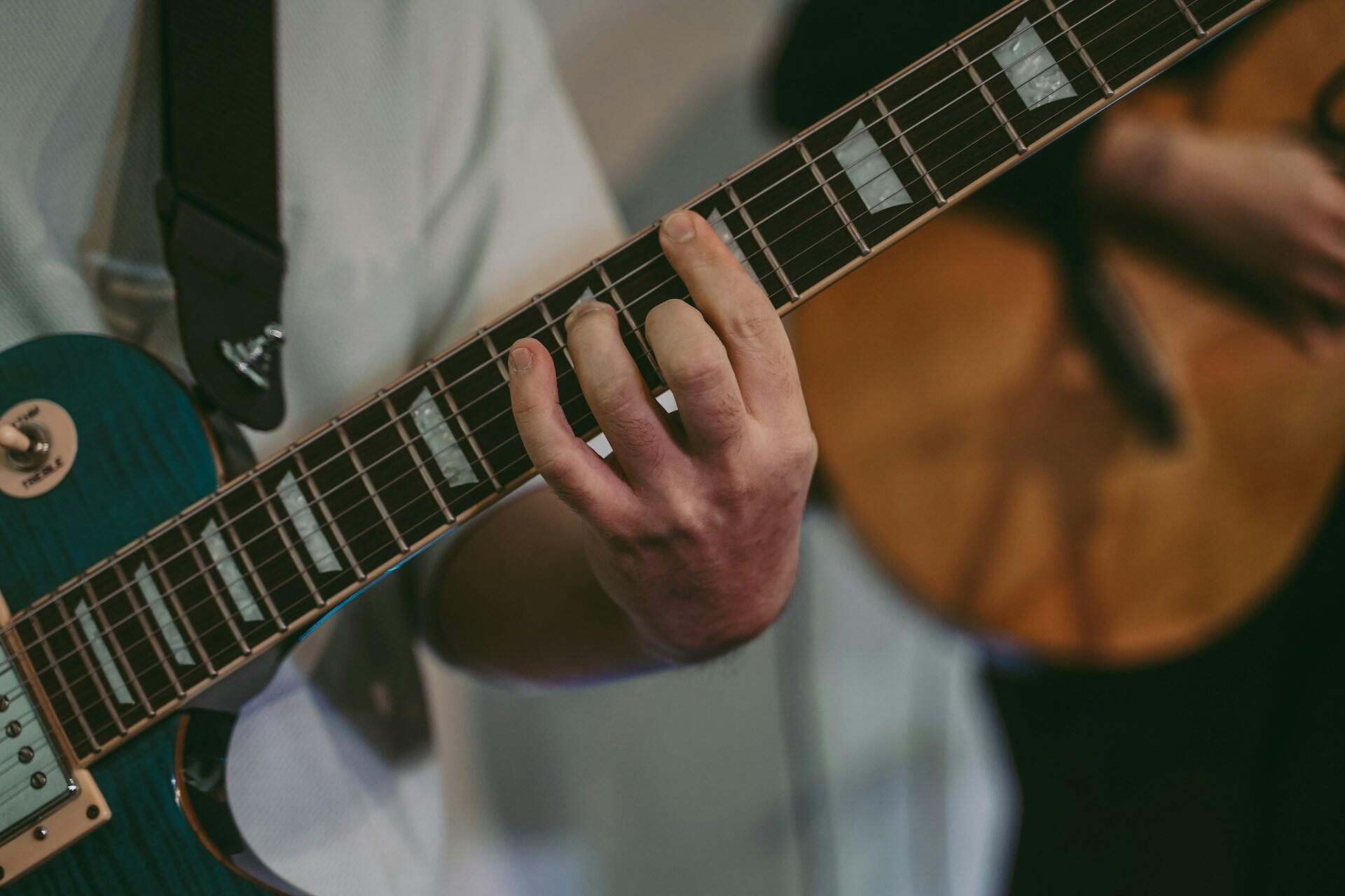 Ranka laiko pirštus ant gitaros stygų.