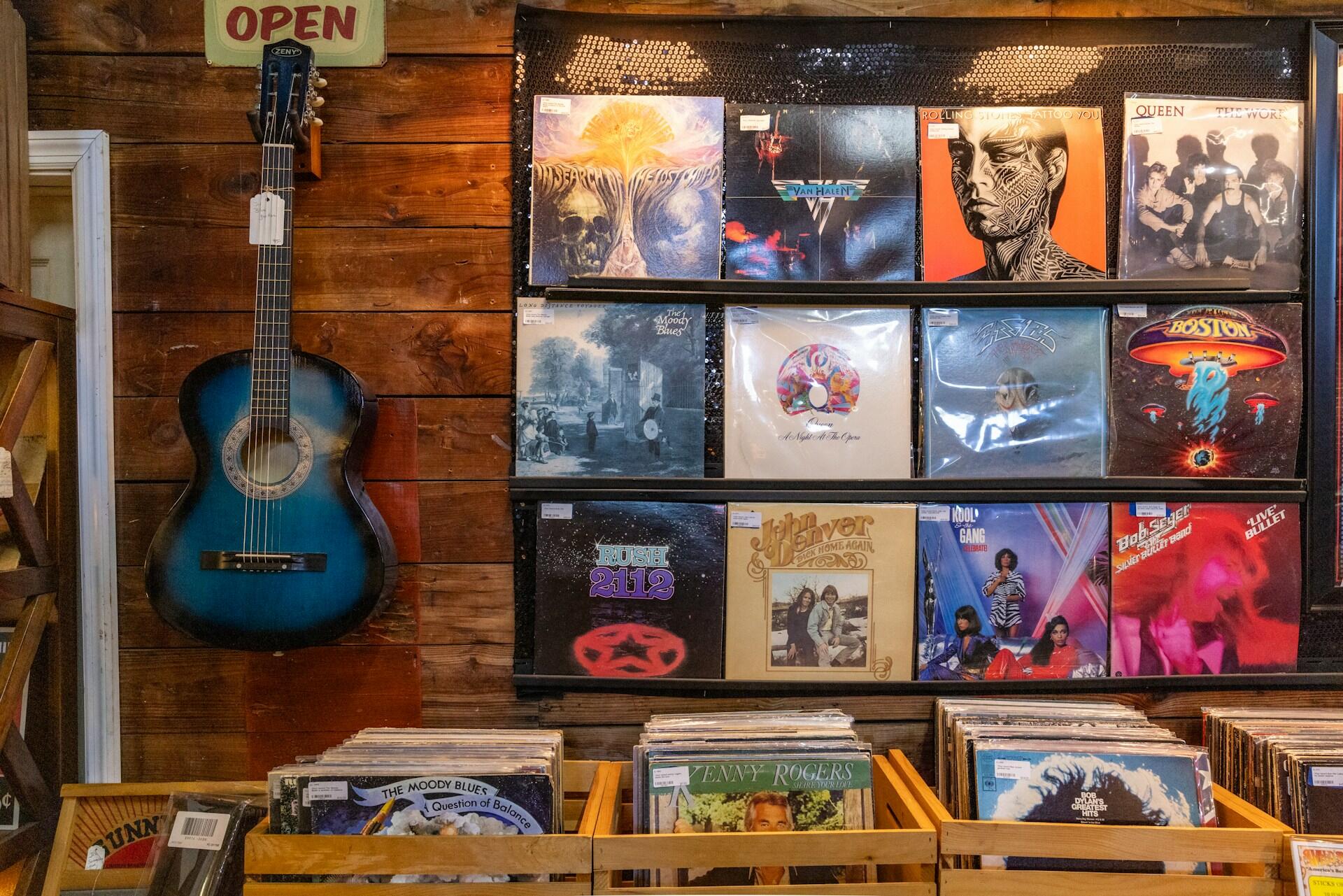 Muzikos parduotuvė su vinilais ir gitara ant sienos