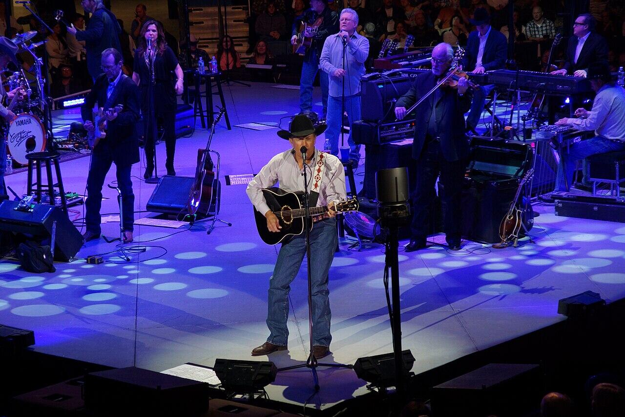 George Strait koncertuoja ant scenos su gitara rankose