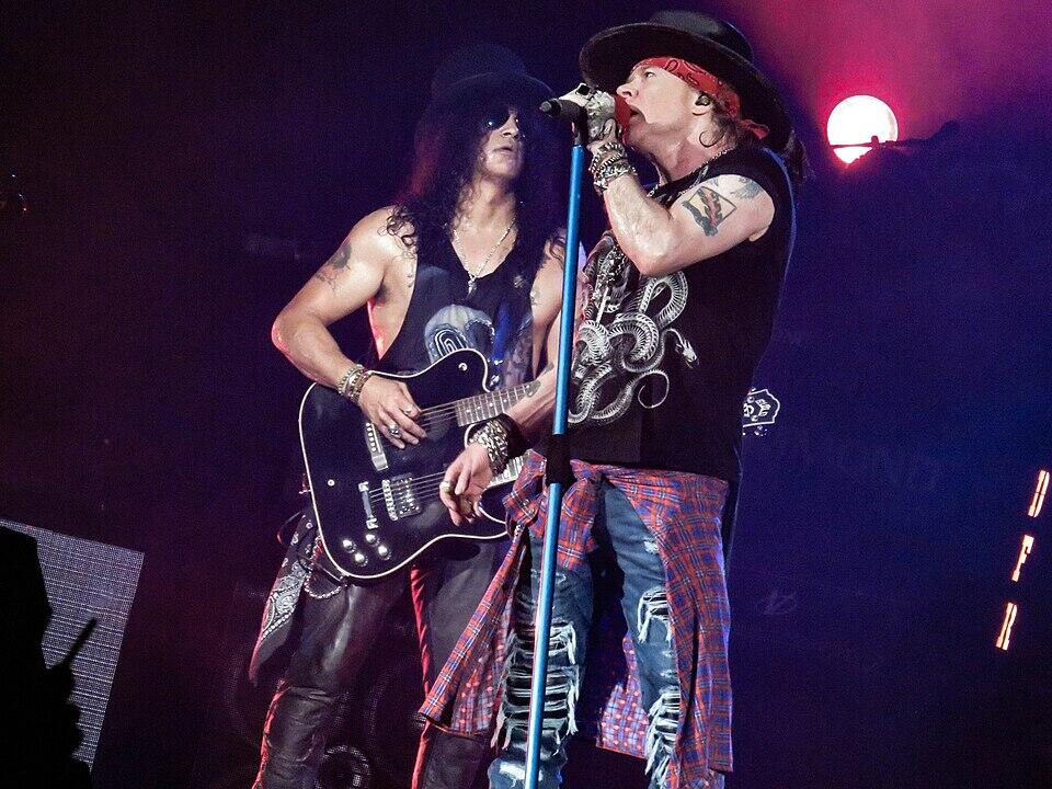 „Guns N' Roses“ atlikėjai ant scenos prie mikrofono