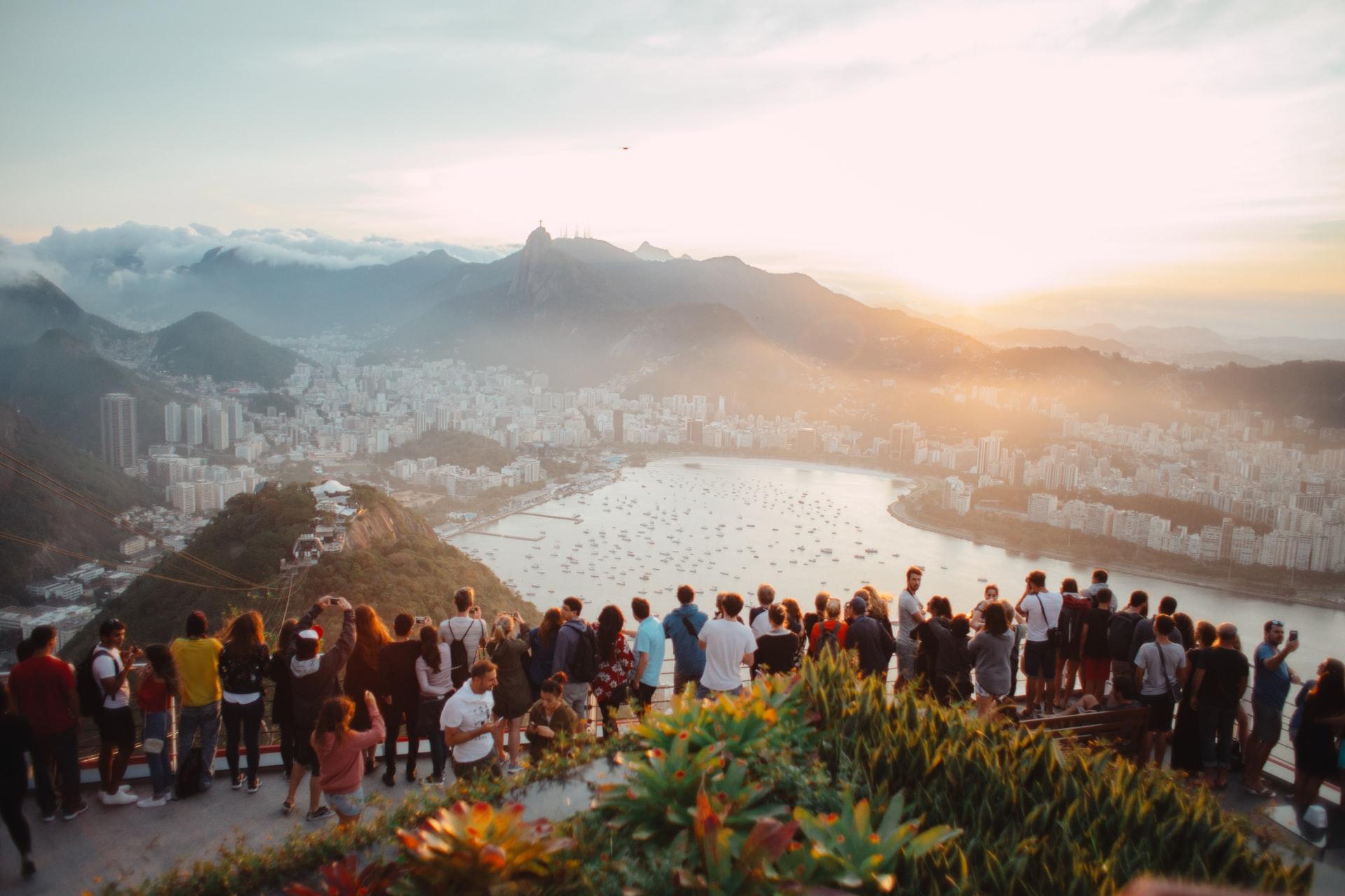 groupe de touristes attroupés devant une vue sur l'eau et les montagnes