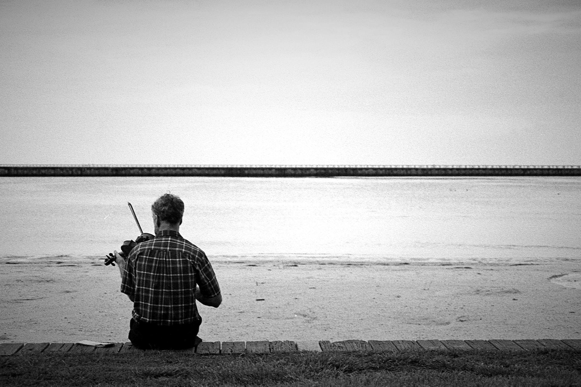homme jouant du violon devant un fleuve