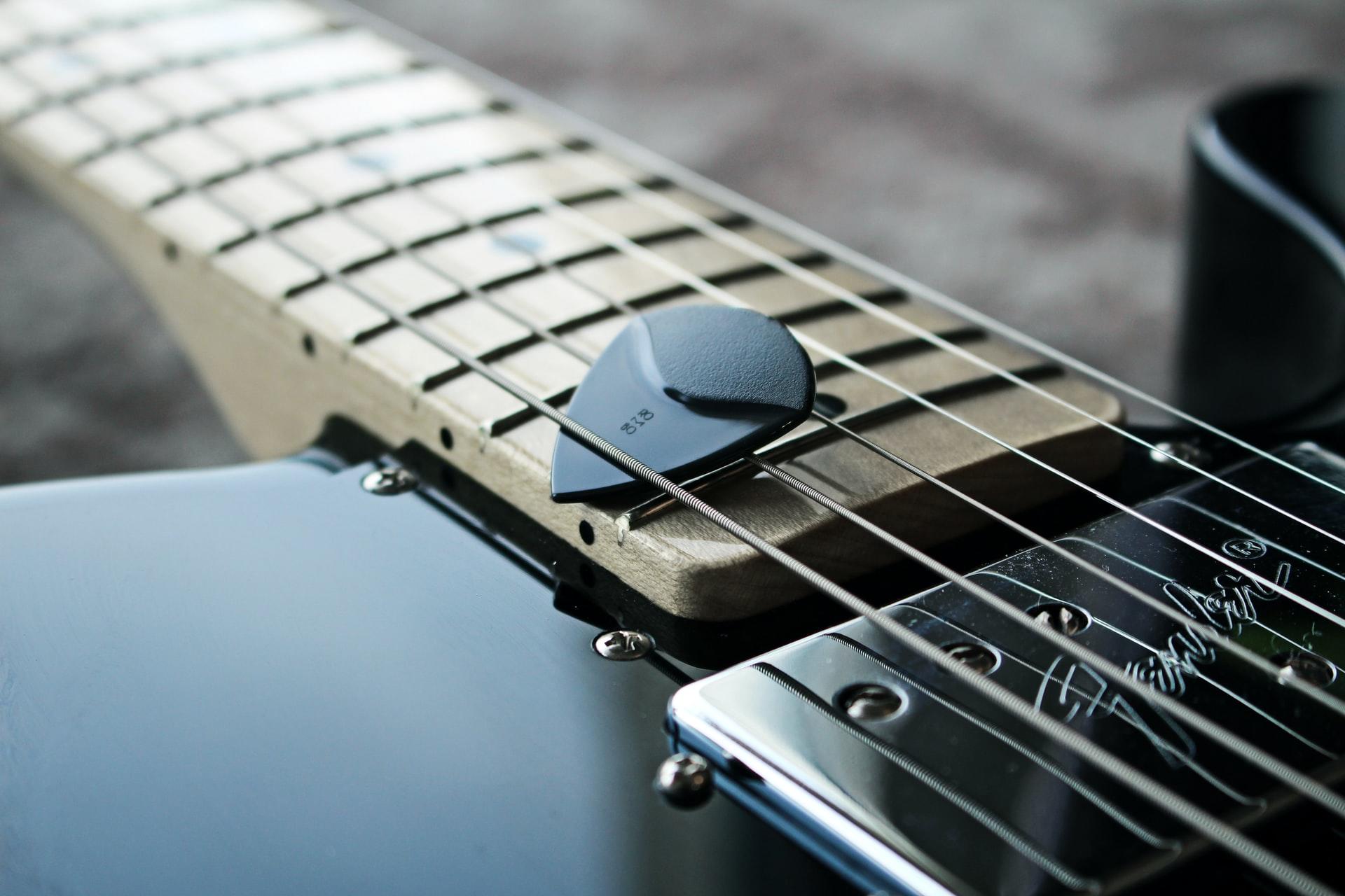 médiator entre les cordes d'une guitare 