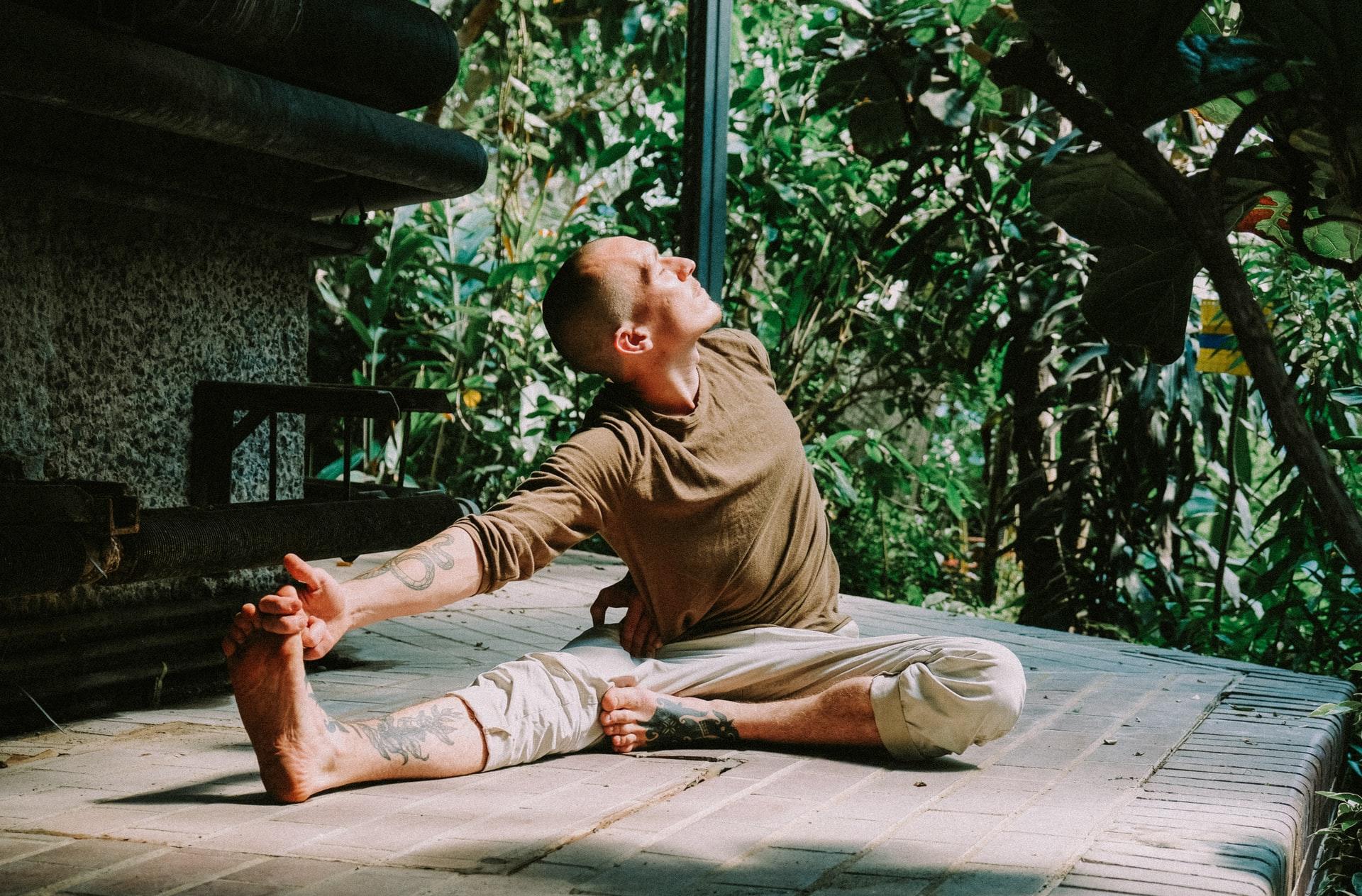 Homme qui fait du yoga dans un jardin