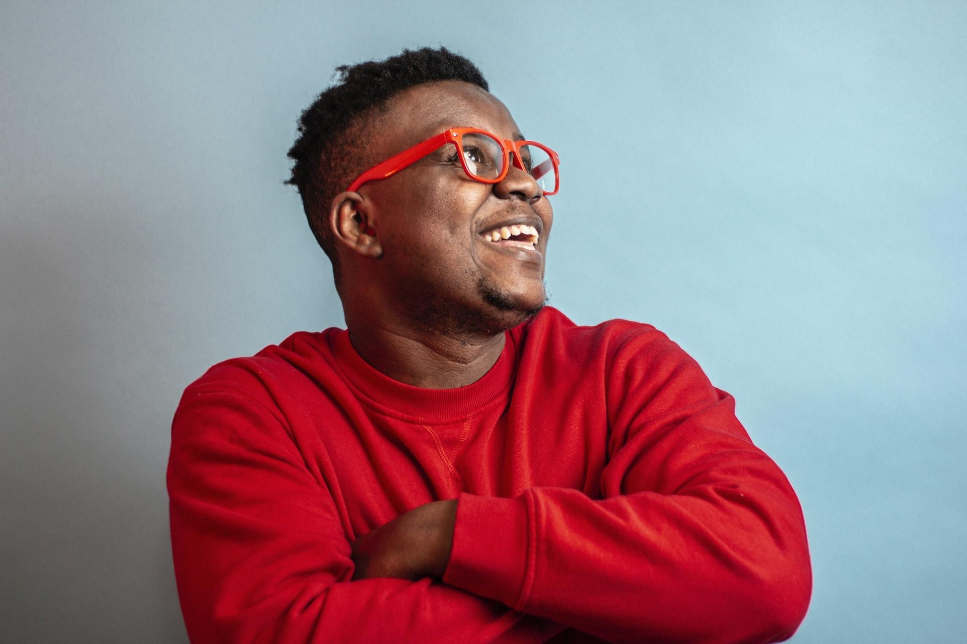 homme souriant avec pull et lunettes rouge