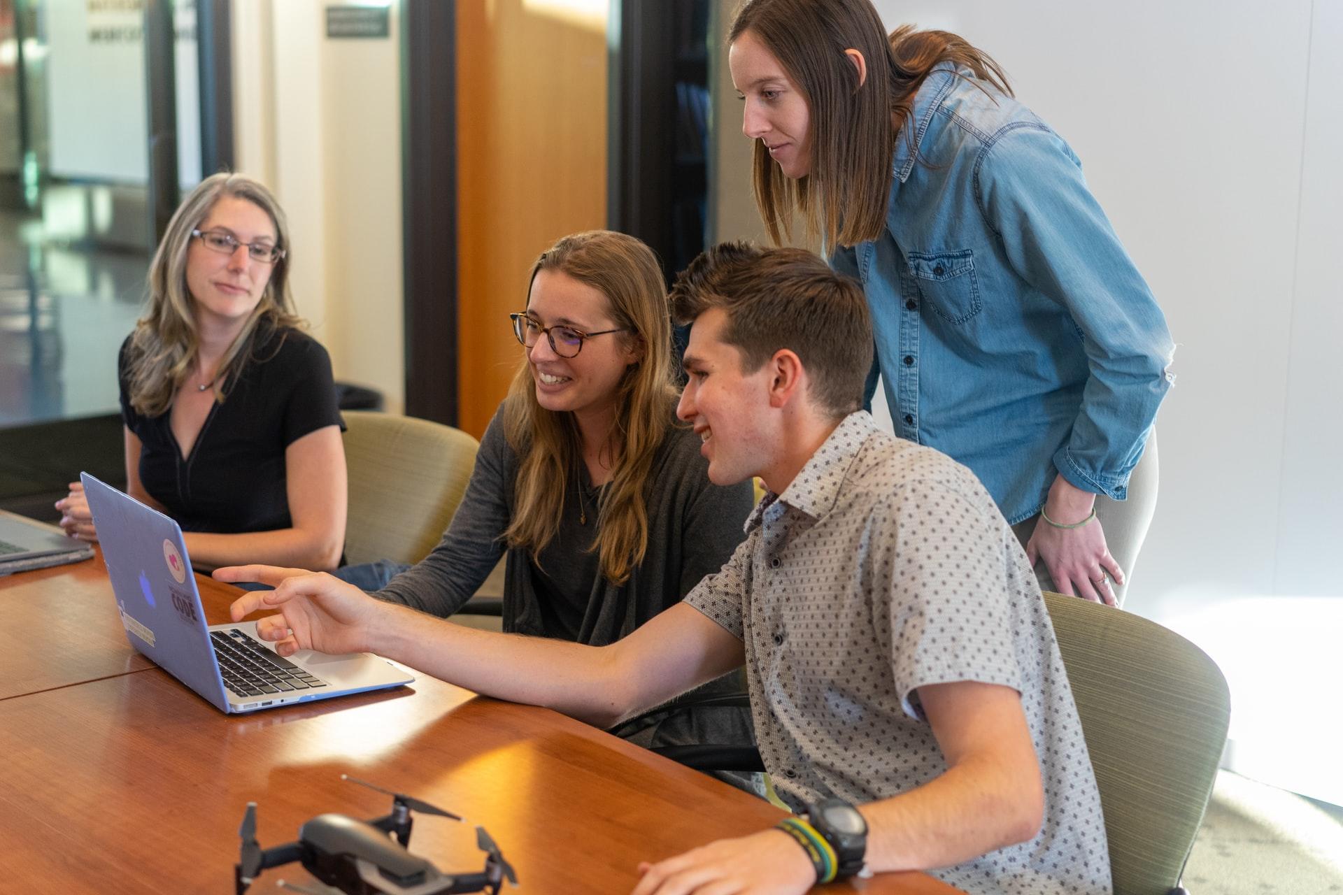 groupe de jeunes souriant et travaillant à une table