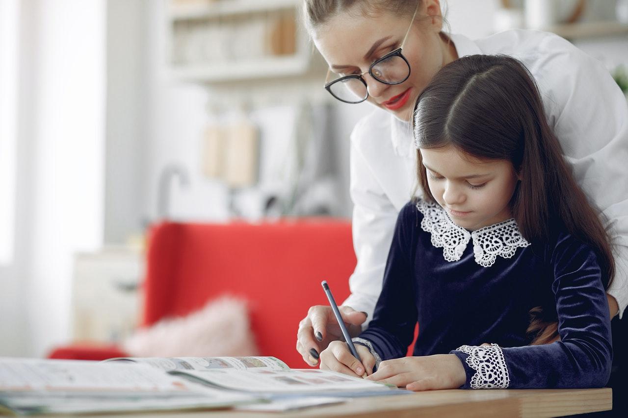 professeure aidant jeune fille à faire ses devoirs