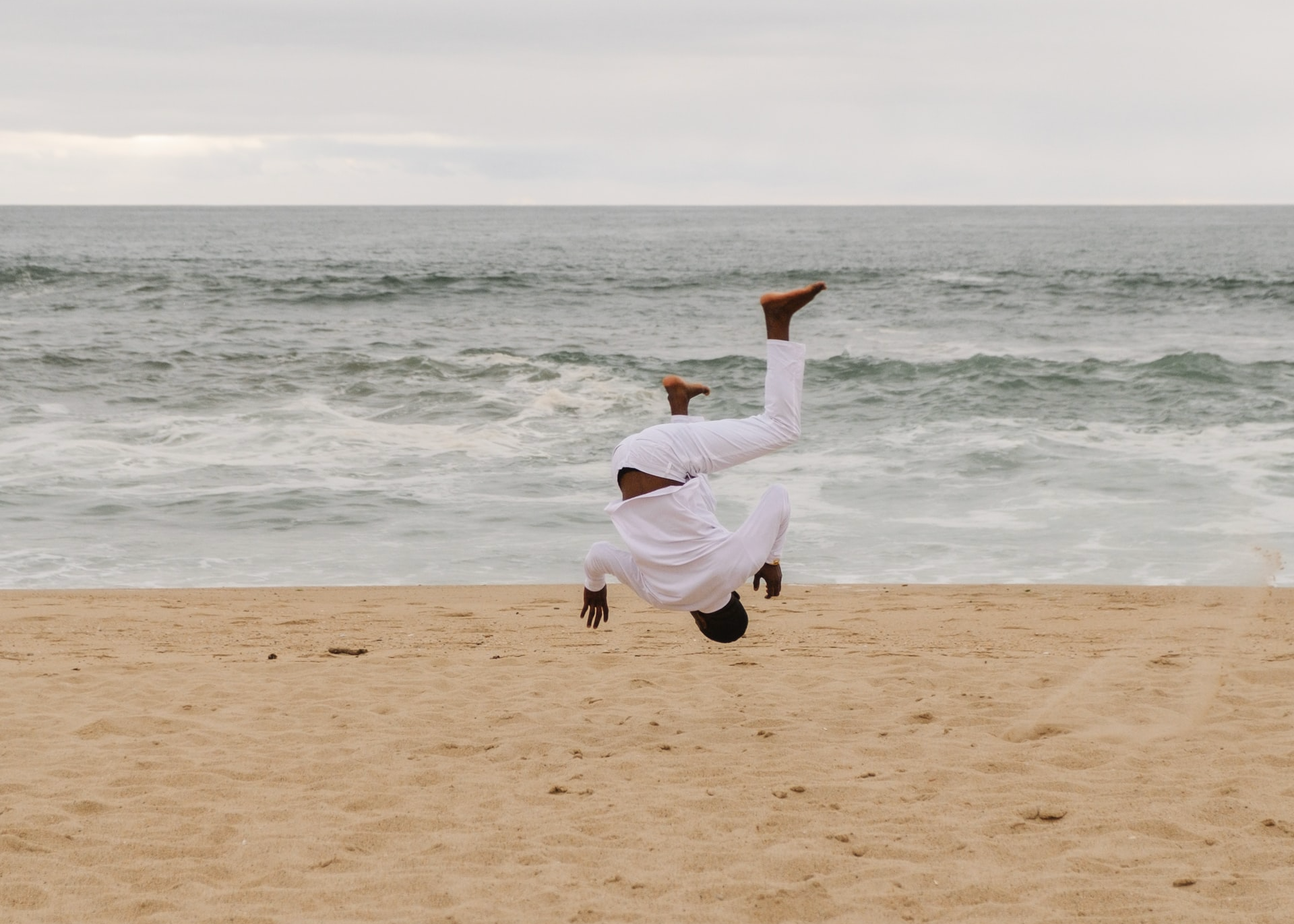 Homme qui danse capoeira sur une plage