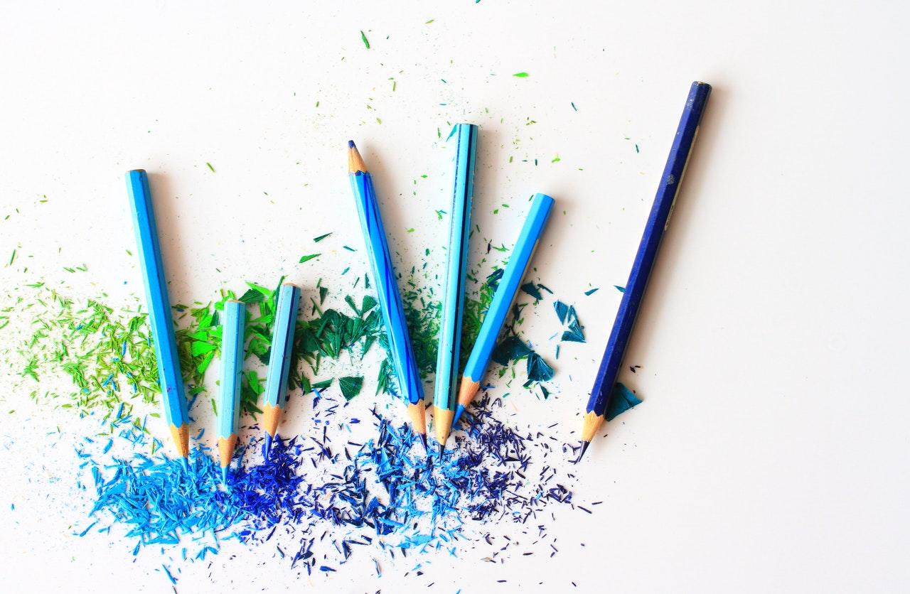 crayons bleus laissant éclatés leurs couleurs disposés sur une feuille blanche