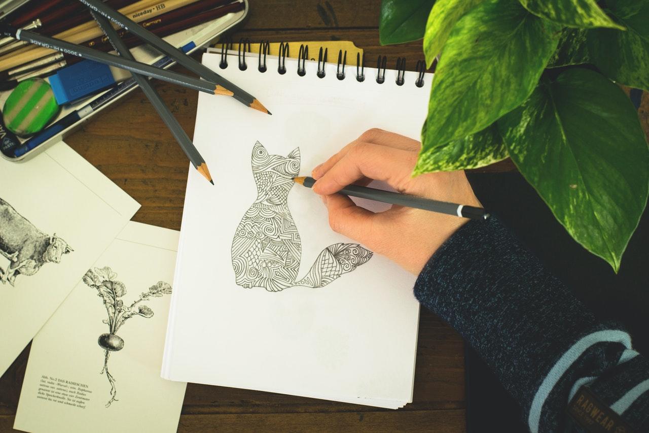 personne dessinant un chat sur un bloc-notes