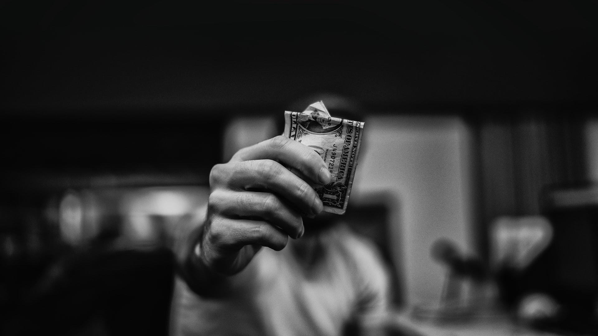 Homme qui tient un dollar américain dans sa main