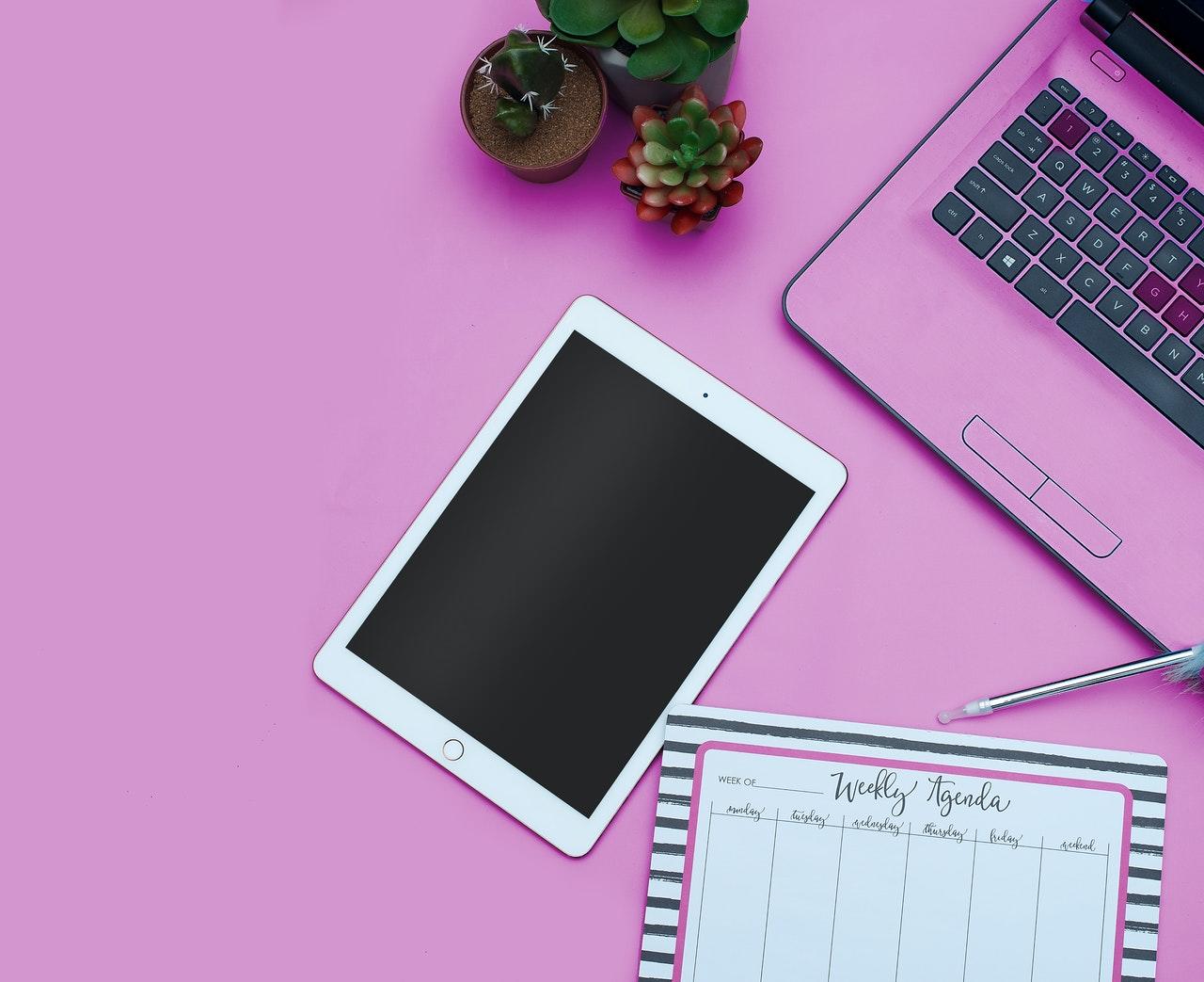 laptop et tablette sur une table rose