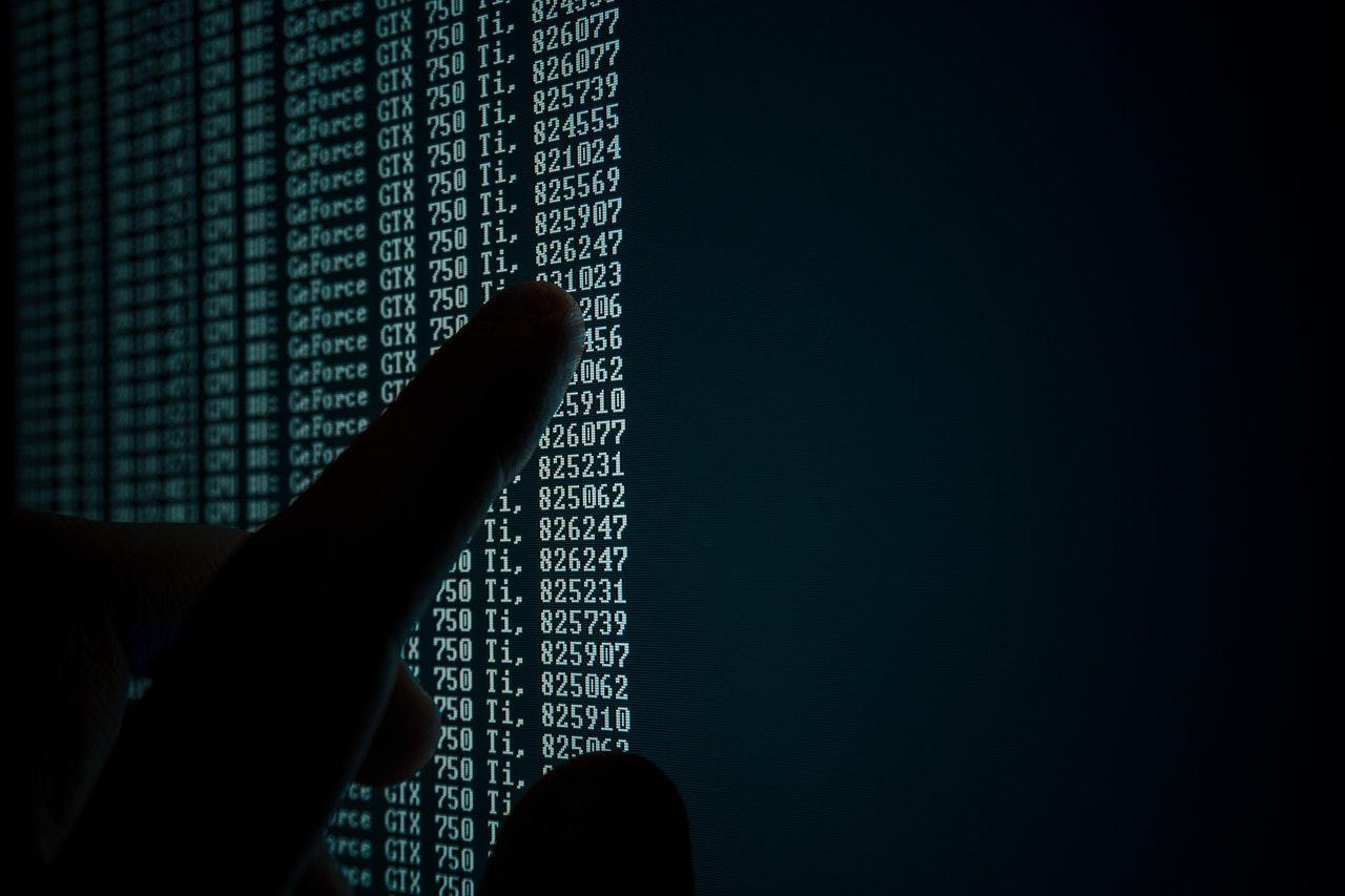 ombre d'un doigt touchant un écran remplit de code