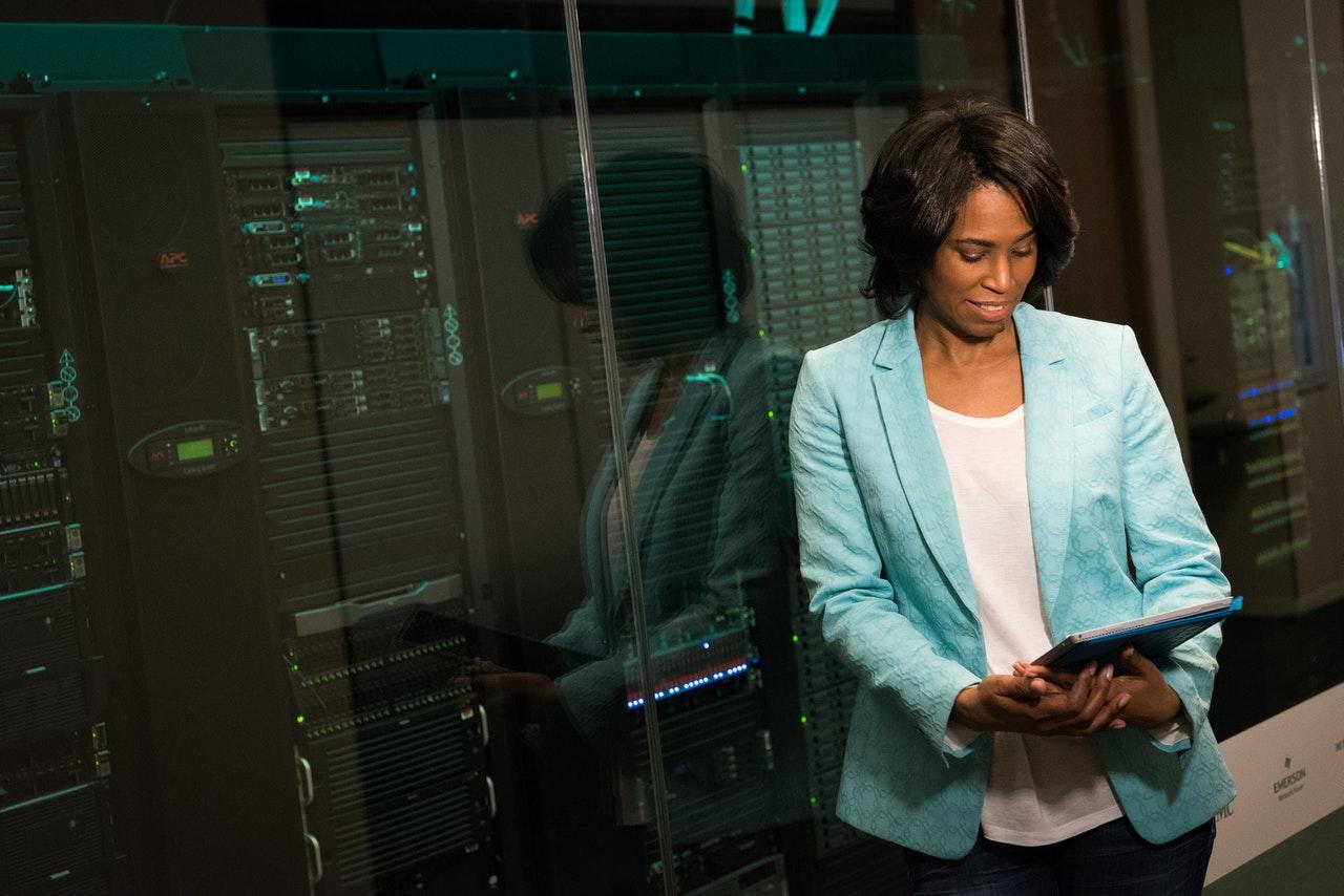 femme en blazer bleu avec un dossier dos à un système informatique complexe