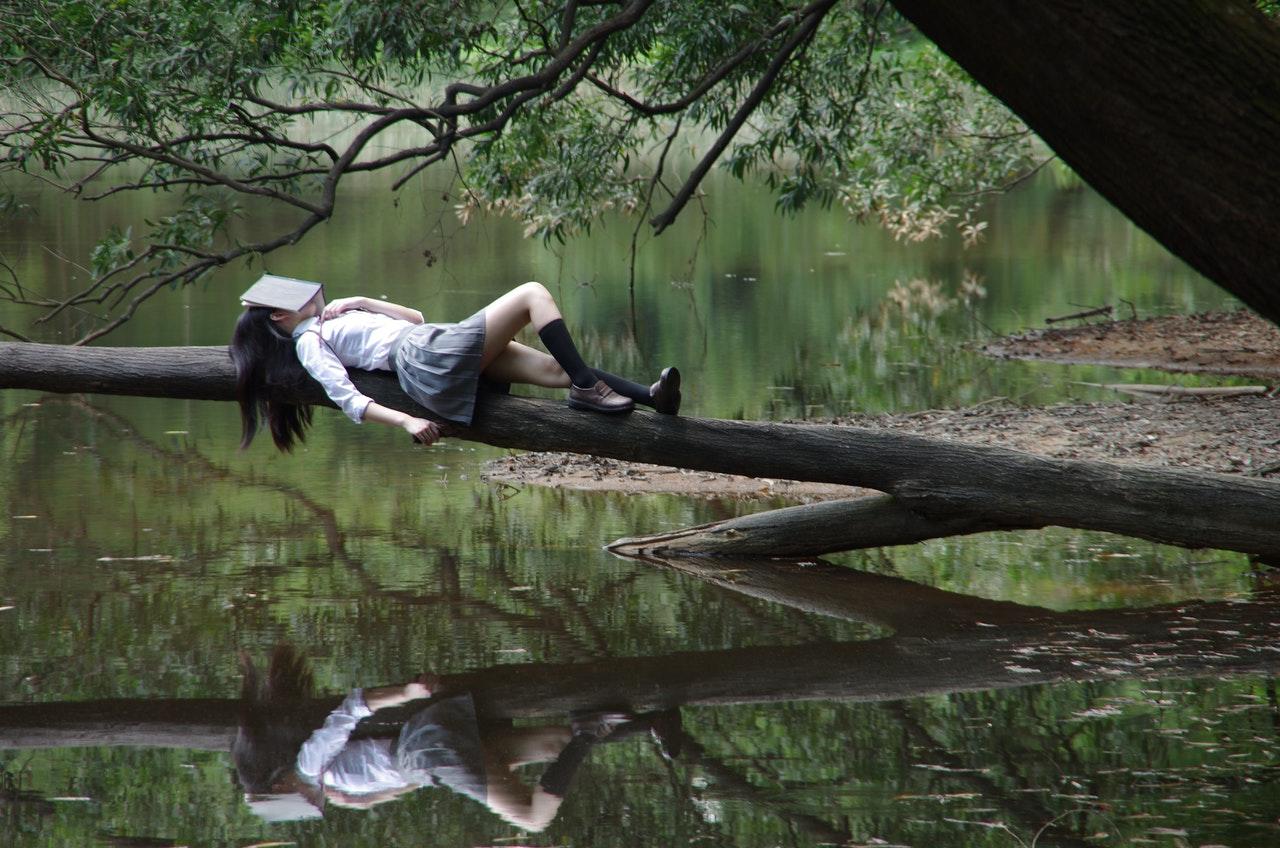 etudiante se reposant sur un arbre au dessus de l eau