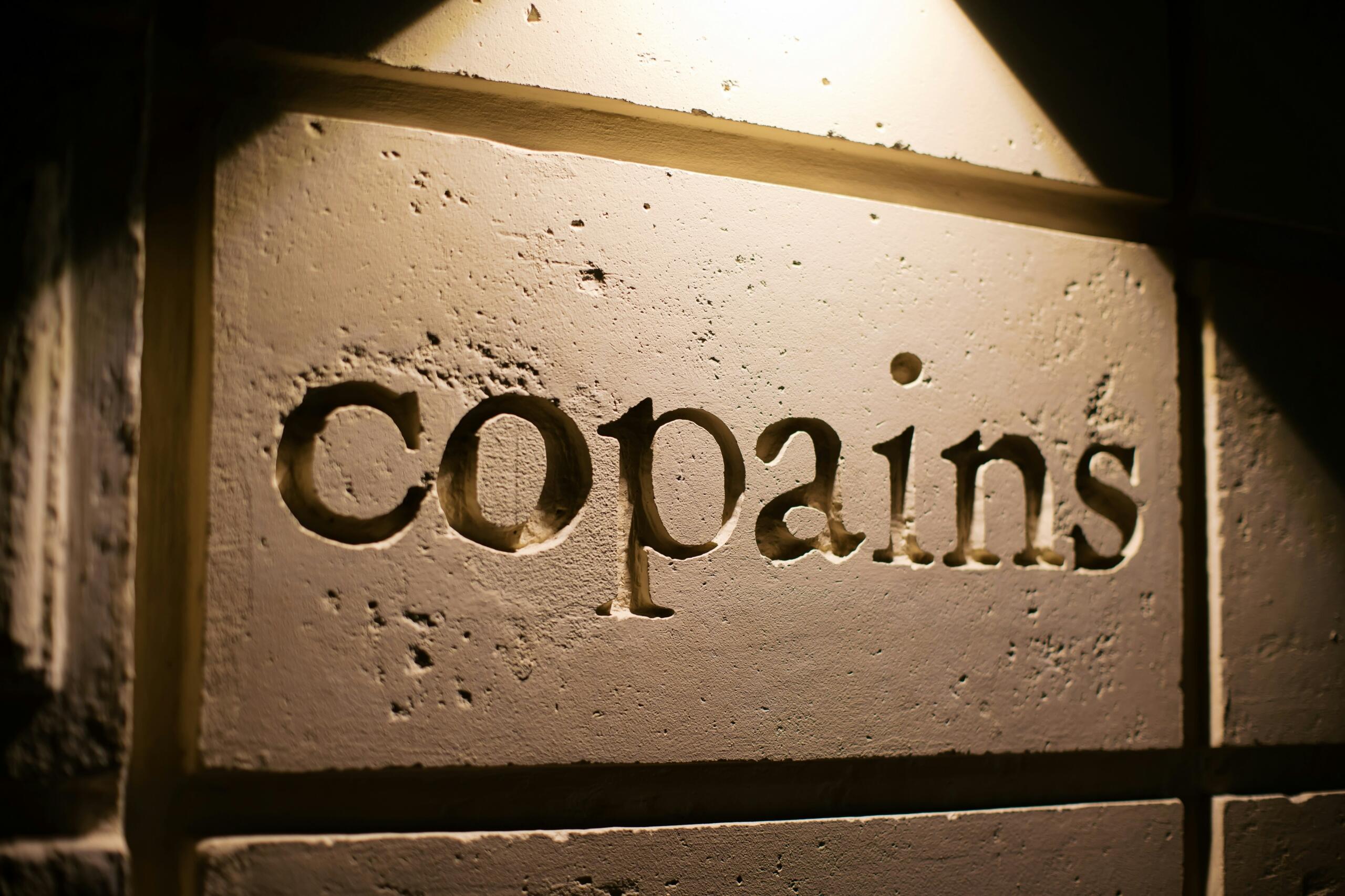 akmens siena ar iegravētu uzrakstu "copains"