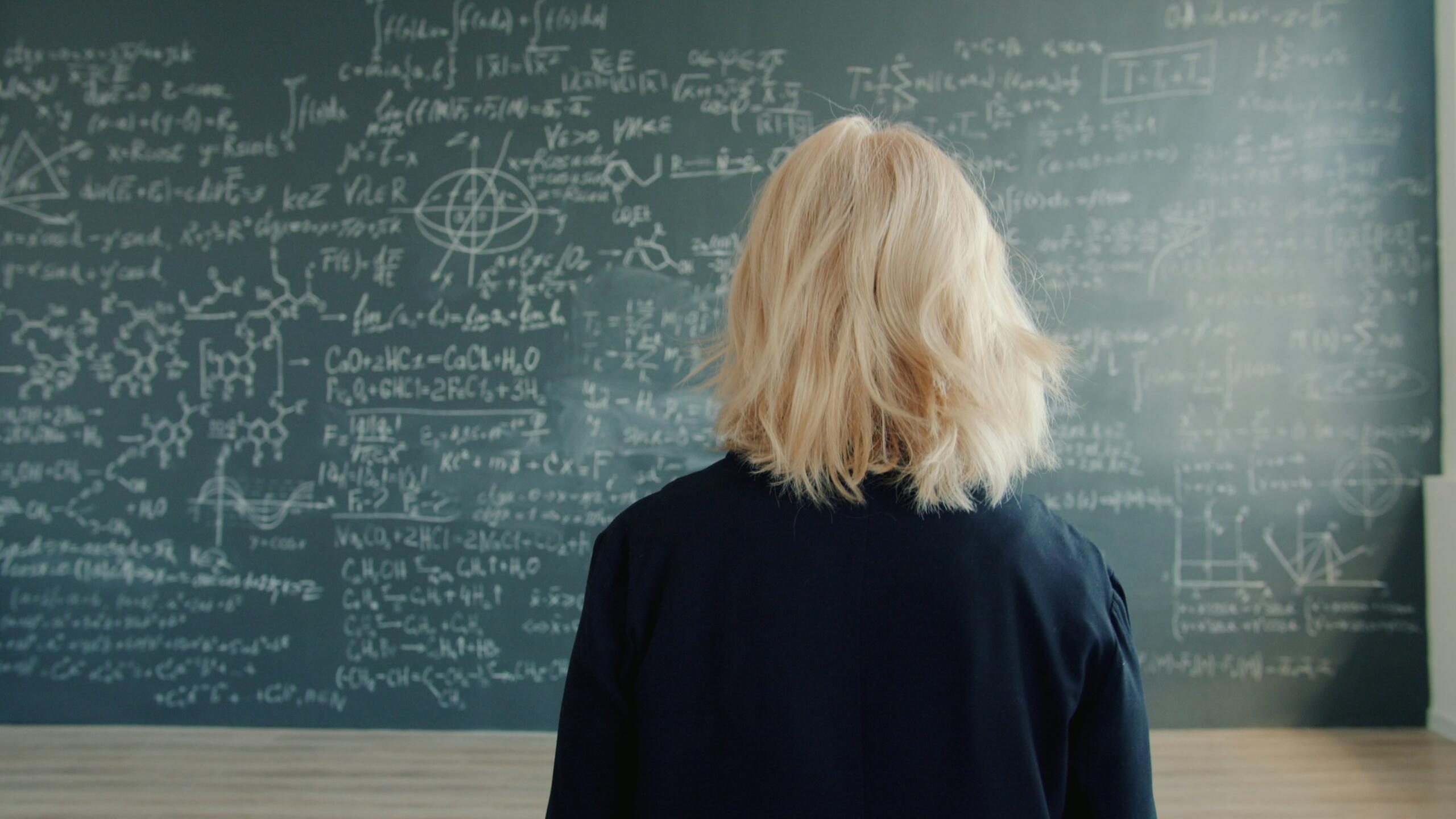 jauna sieviete domā pie matematikas tāfeles