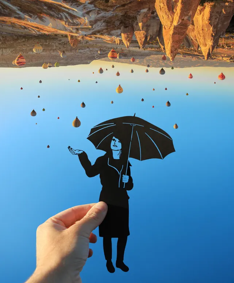 Roka tur sievietes silueta figūru ar lietussargu pret zilām debesīm.