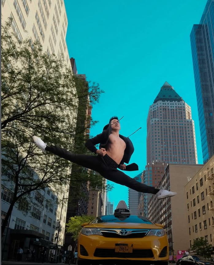 Vīrietis dinamiskā lēcienā virs taksometra pilsētas ielā.