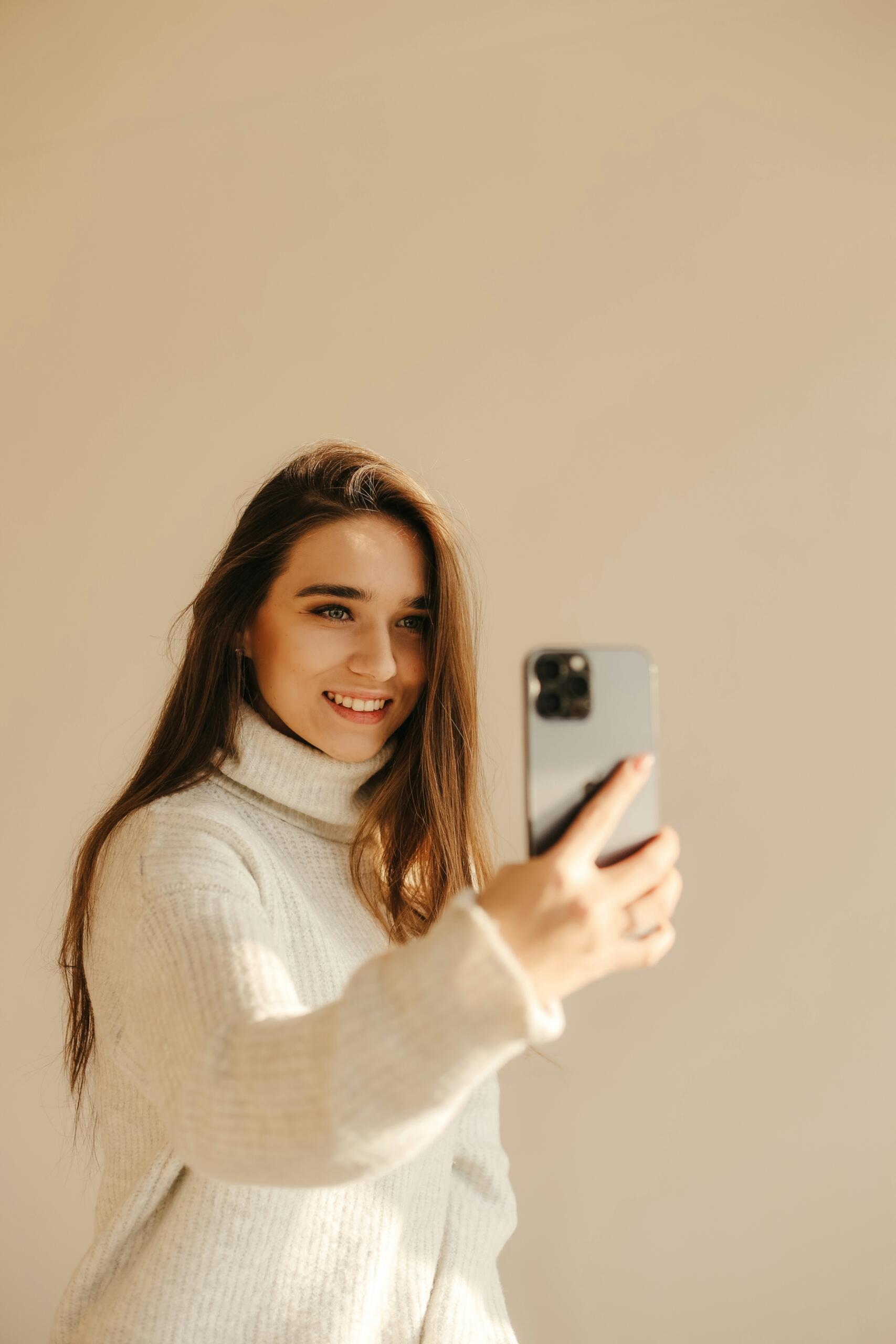 Jauna sieviete smaida un uzņem selfiju ar viedtālruni.