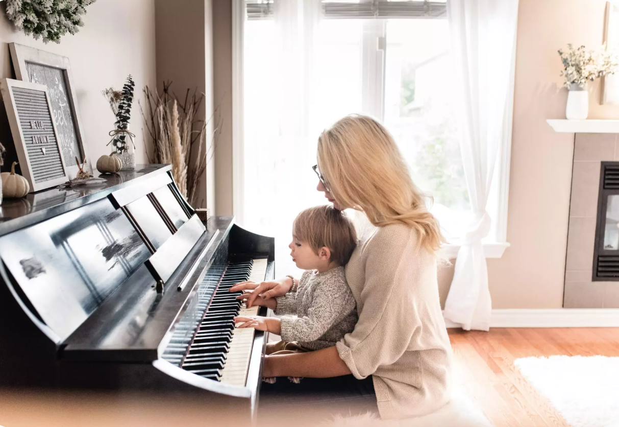 Sieviete māca bērnam spēlēt klavieres.