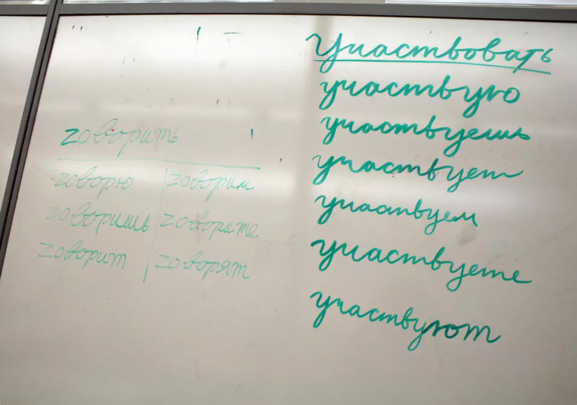 Uz tāfeles uzrakstīta krievu darbības vārdu locīšana dažādās personās.