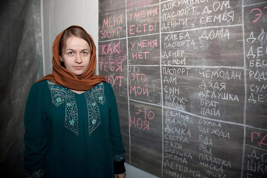 Sieviete pie tāfeles ar krievu valodas vārdiem un frāzēm.