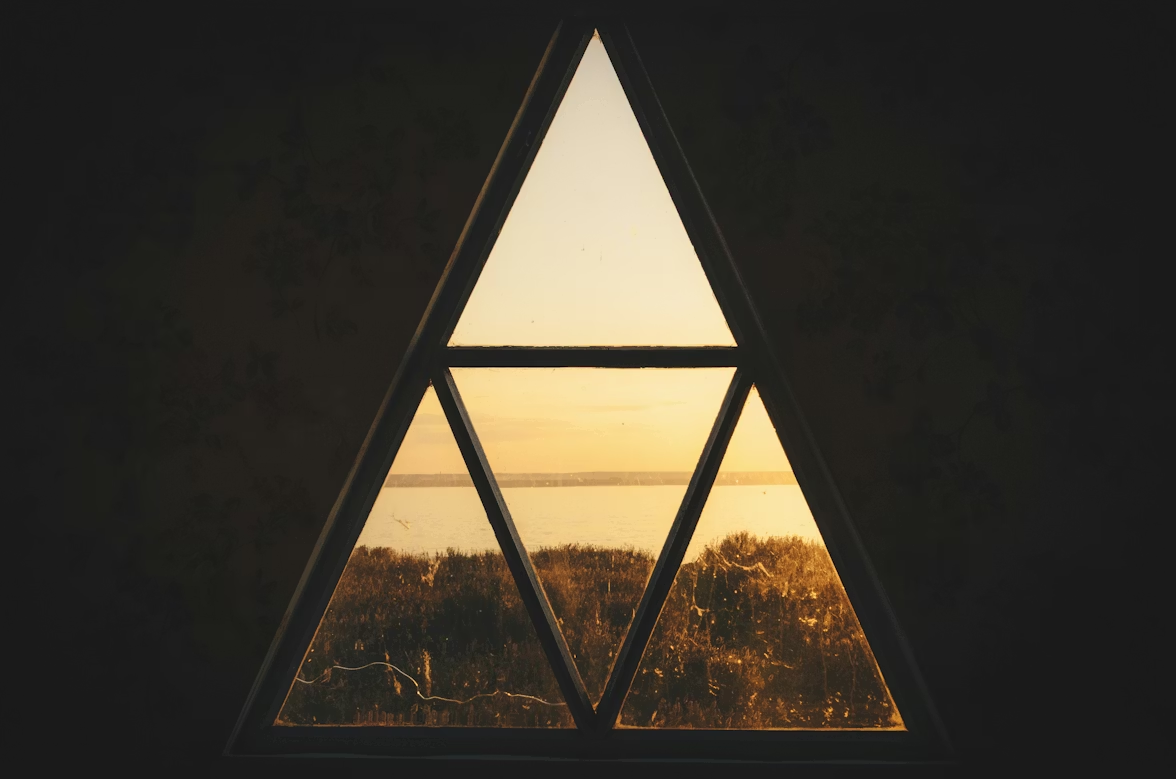 Trijstūra formas logs ar ainavu saulrietā.