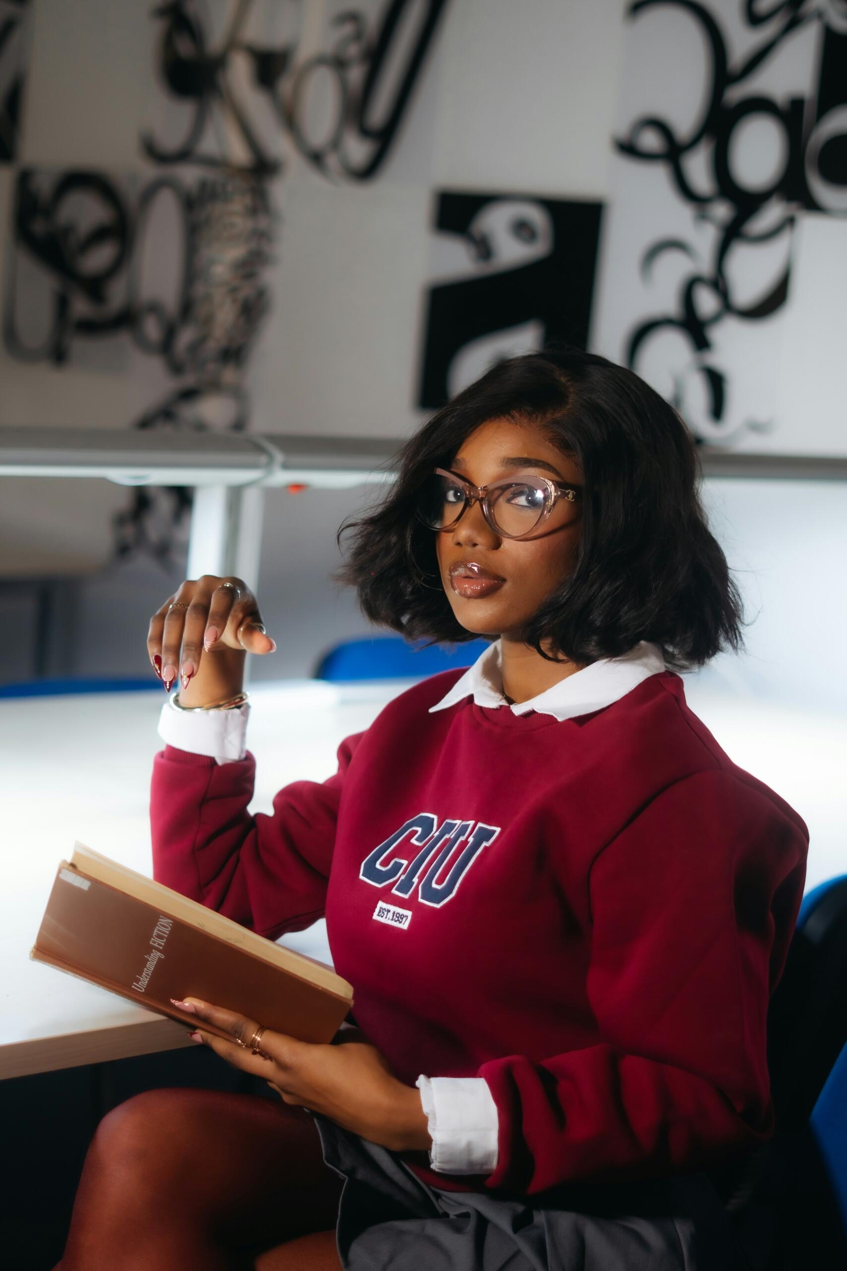 Studente ar grāmatu rokās sēž auditorijā.