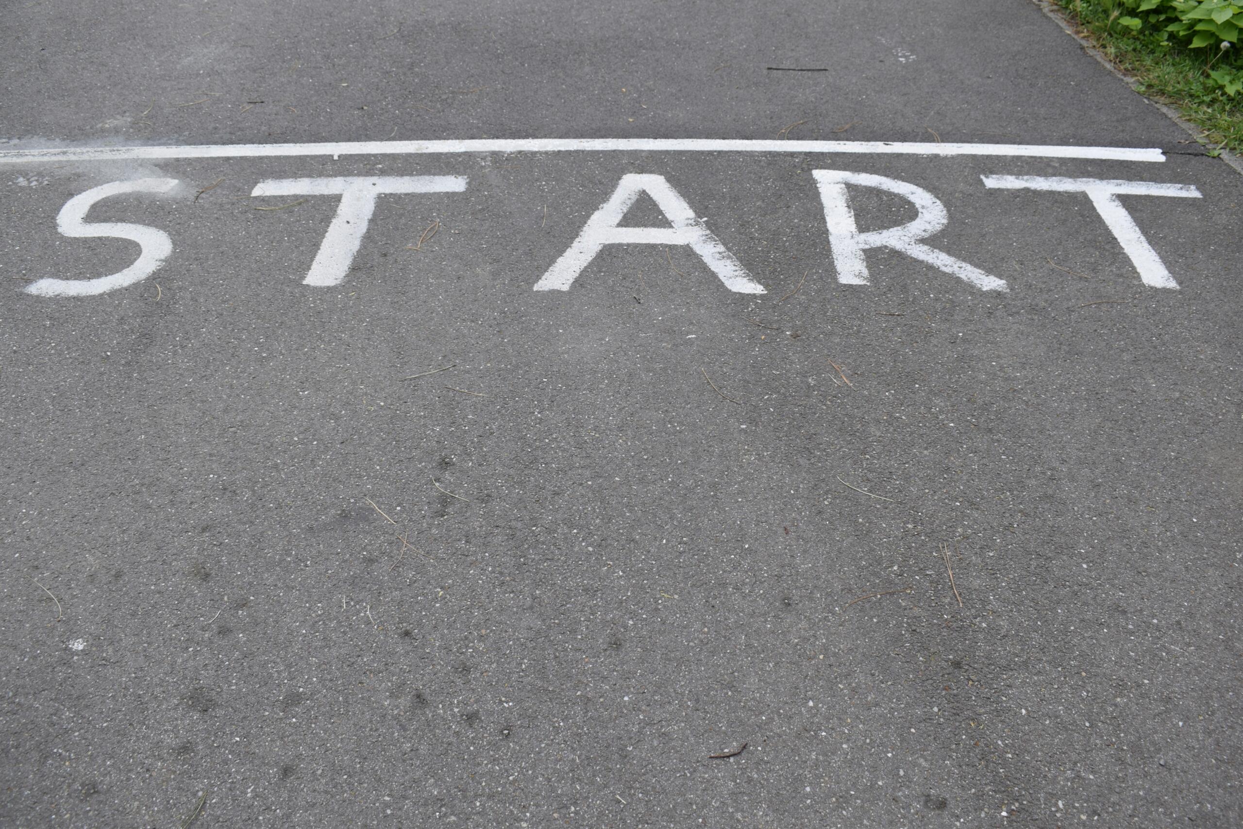 Uz asfalta ar baltu krāsu uzrakstīts “START”.