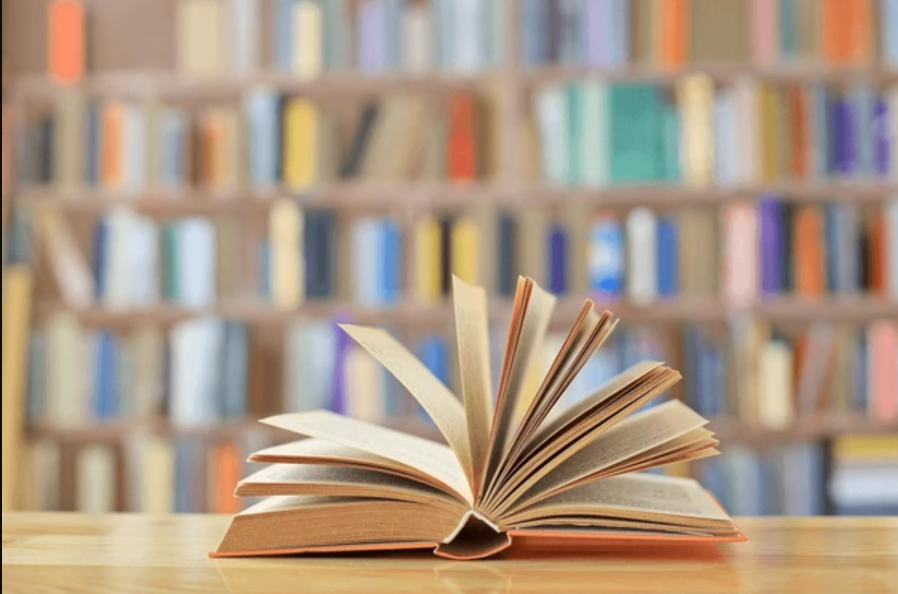 Uz galda bibliotekā stāv atvērta grāmata.