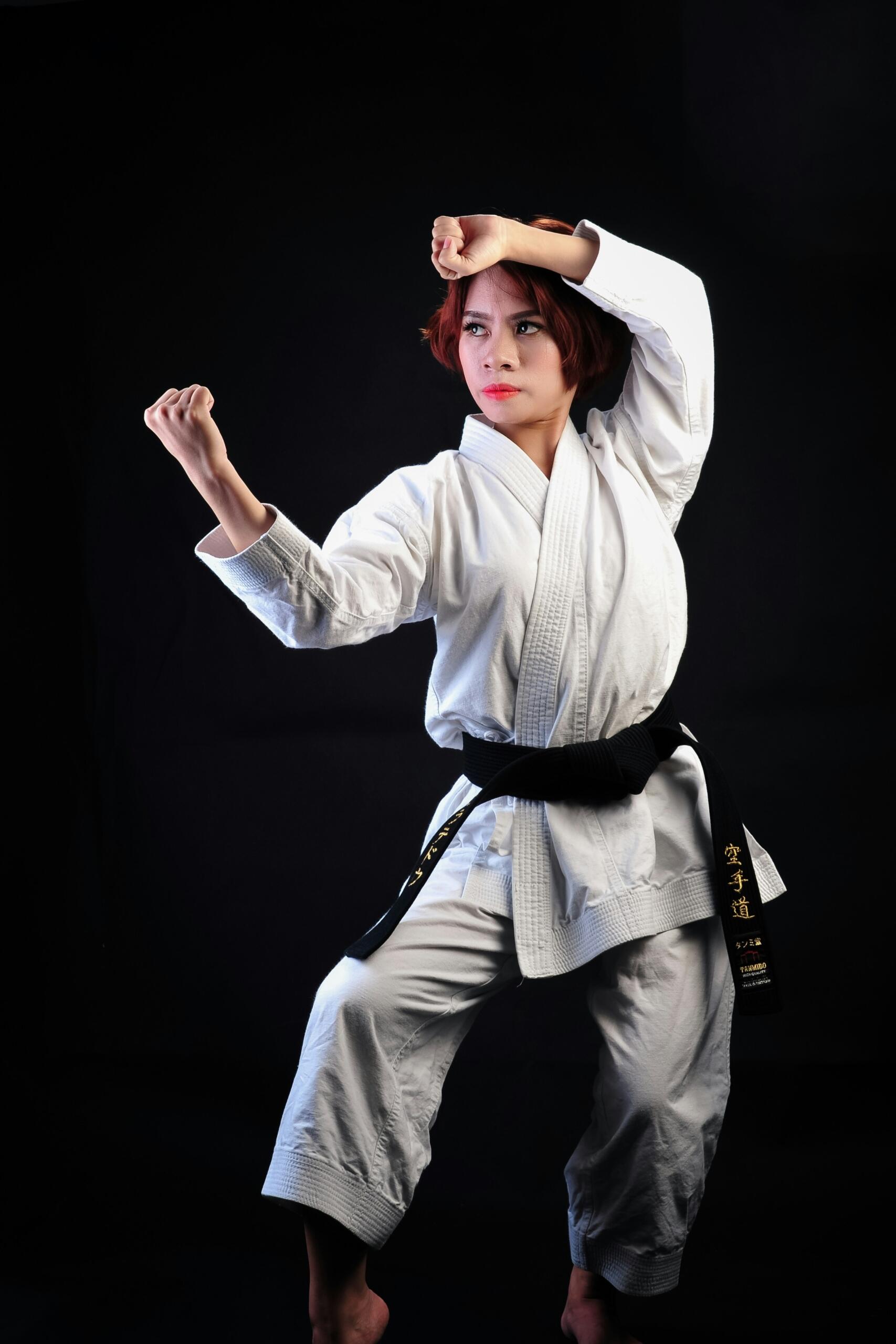 Sieviete baltā kimono ieņem cīņas pozu.