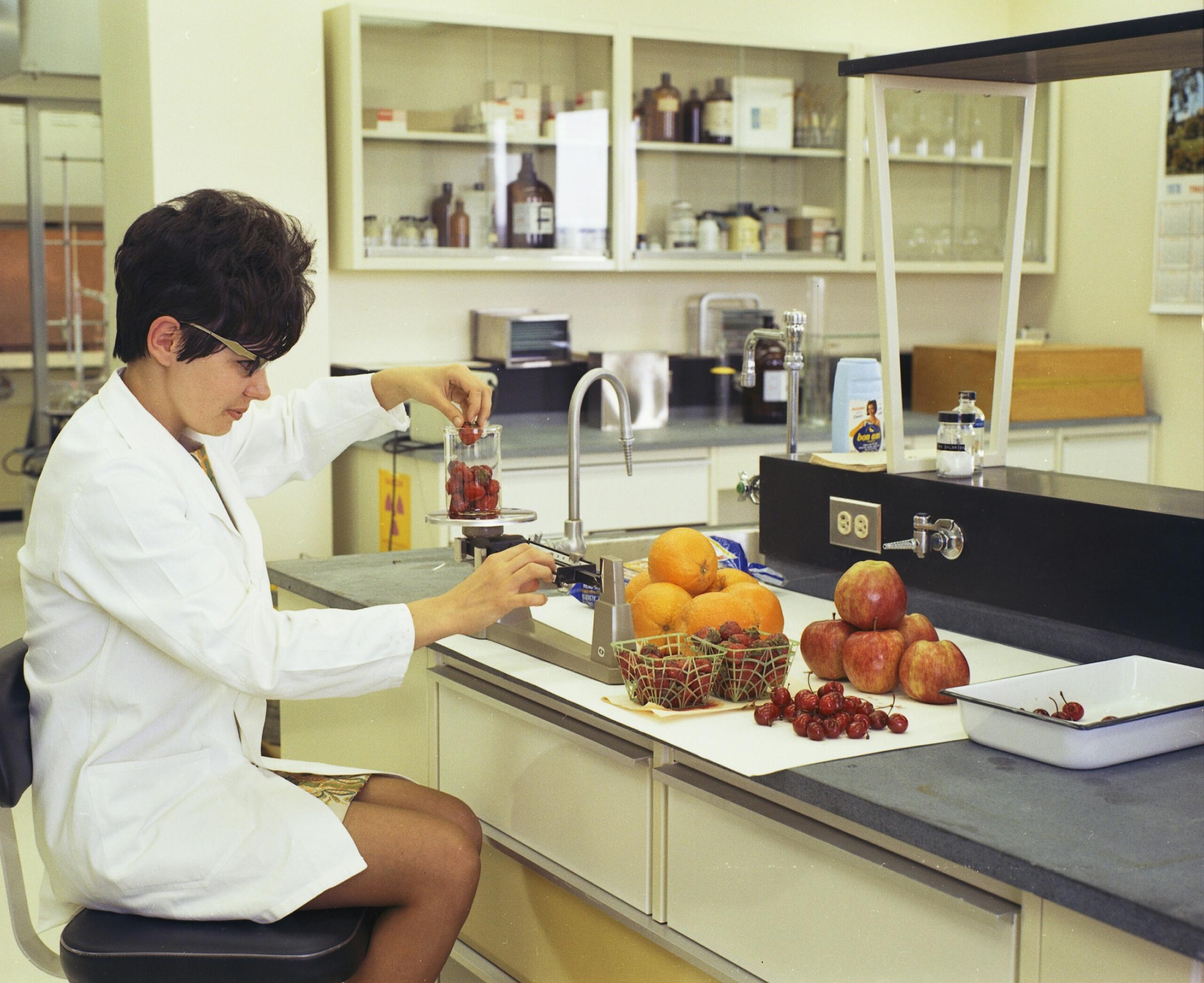 ķīmiķe veic pētījumu laboratorijā ar augļiem