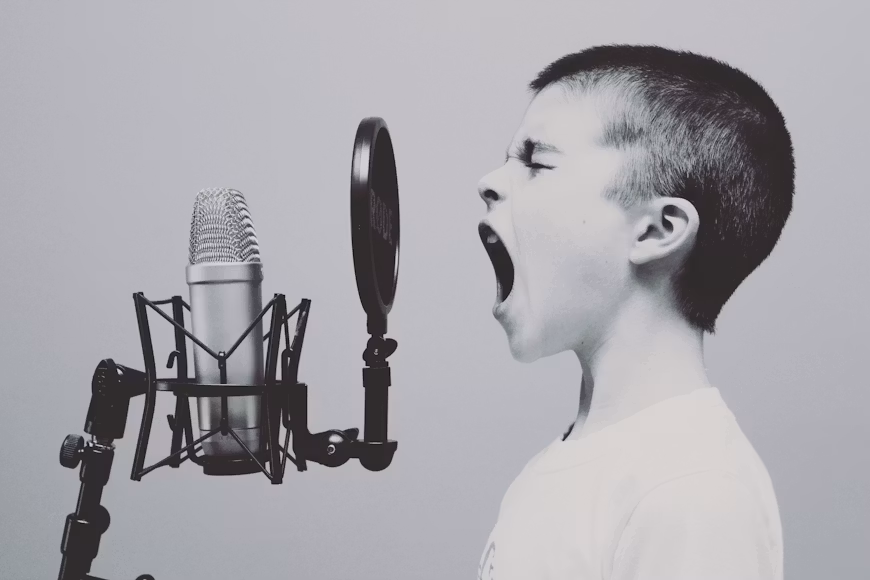 Na slici je prikazan dječak koji pjeva tokom probe. On se nalazi u muzičkom okruženju i vježba svoje vokalne sposobnosti.