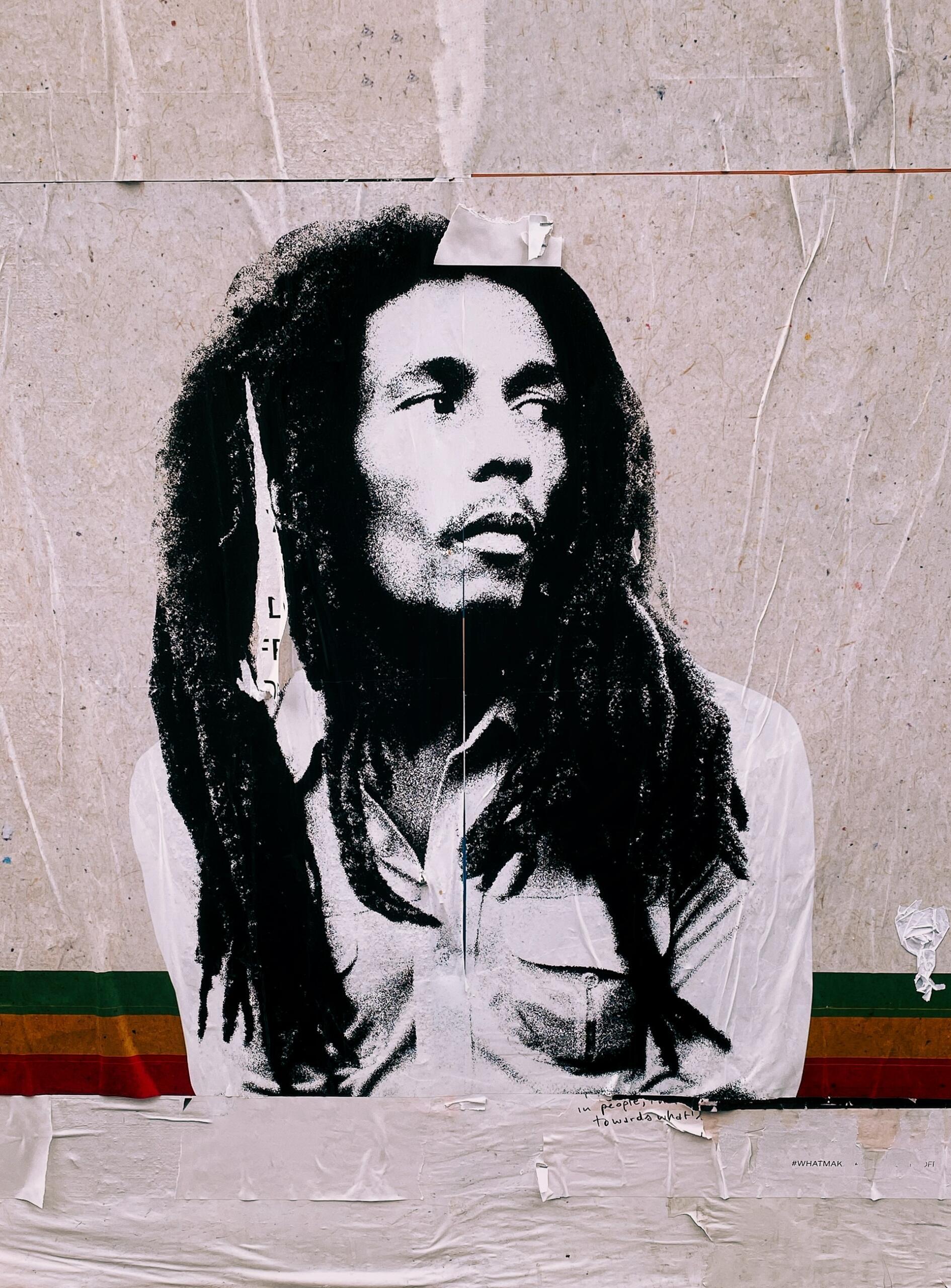 A black-and-white mural of a person with long, textured hair, against a textured background with colorful stripes.