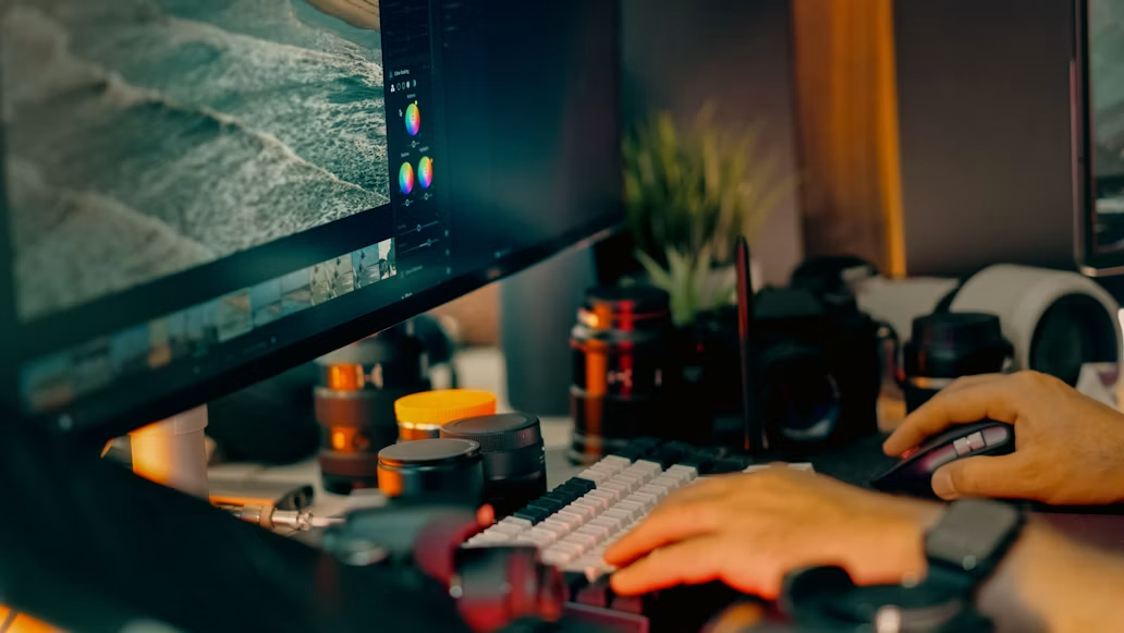 Fotograf prilagođava tonove i boje slika koristeći profesionalni softver na visokokvalitetnom monitoru u studiju. Prikaz procesa obrade fotografija, kolor grejdinga i rada u radnom okruženju posvećenom vizuelnoj umjetnosti.