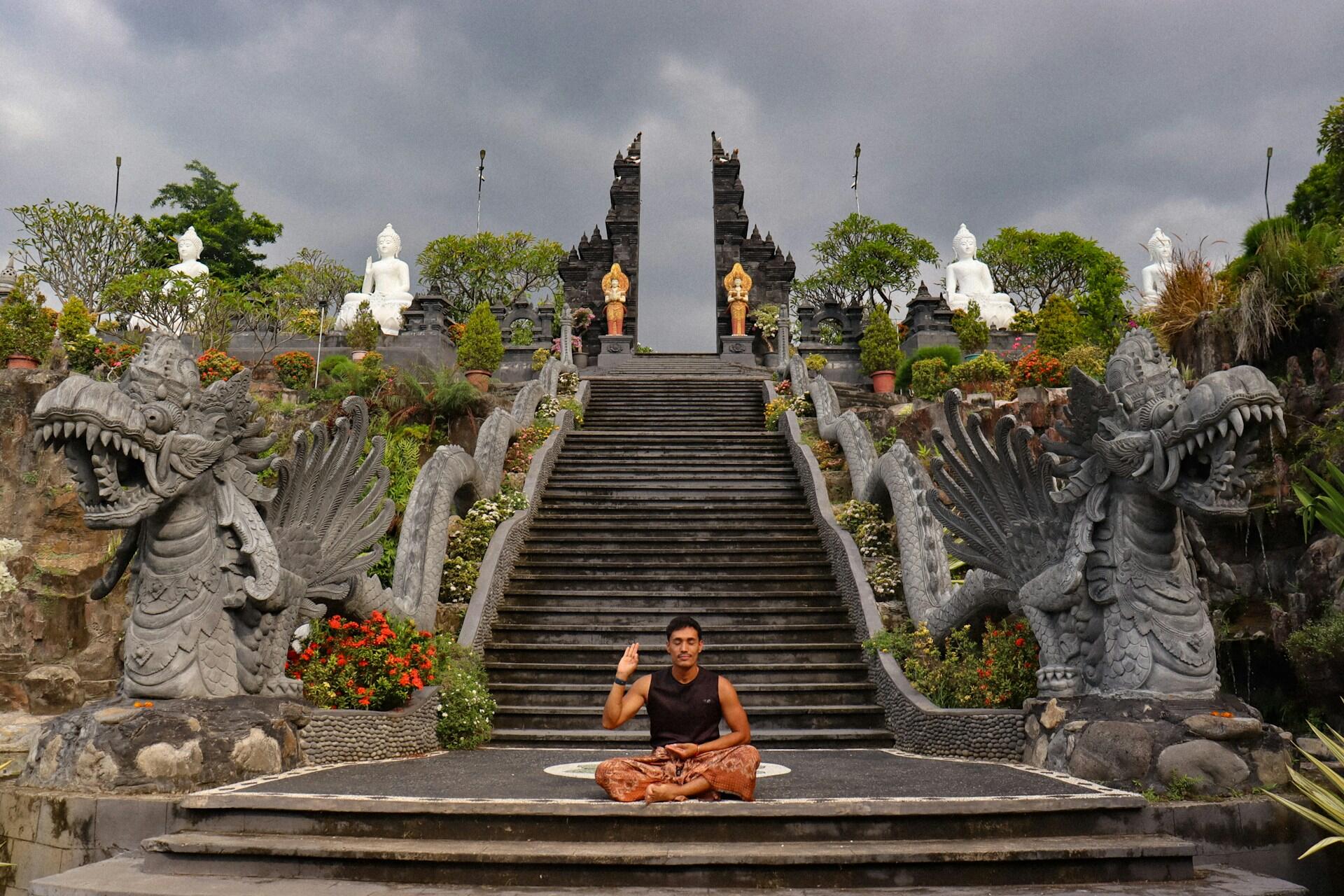 Person meditating in front of a temple staircase representing the spiritual roots and history of yoga