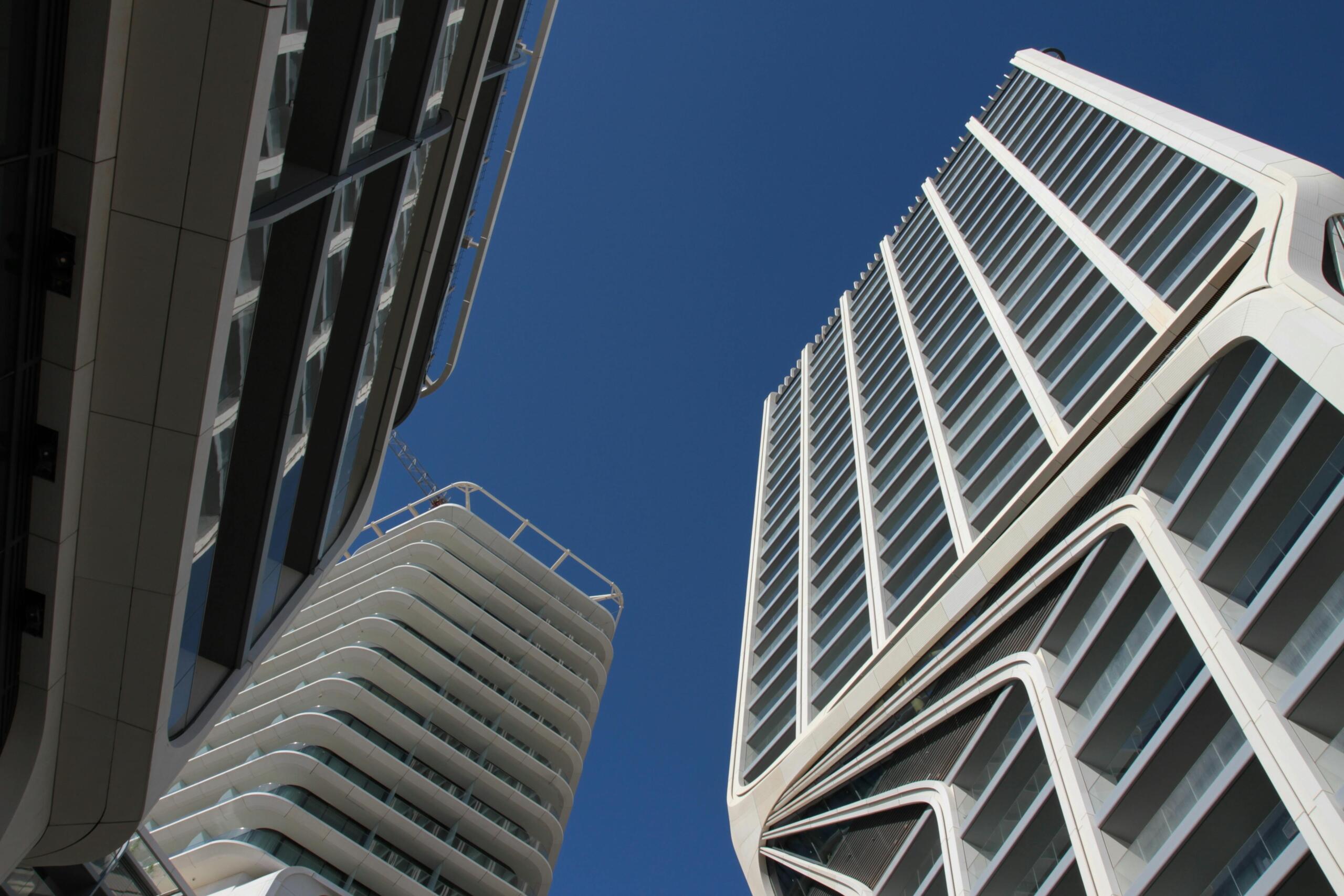 A low‑angle view of modern high‑rise buildings with glass balconies and crisp lines set against a deep blue sky in St. Julian’s, Malta.